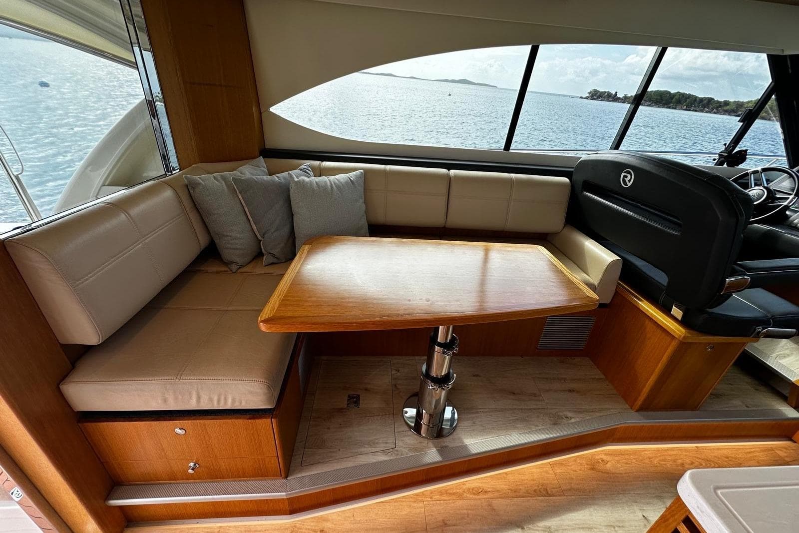 Interior of 2020 Riviera 395 SUV with seating and table, overlooking water.
