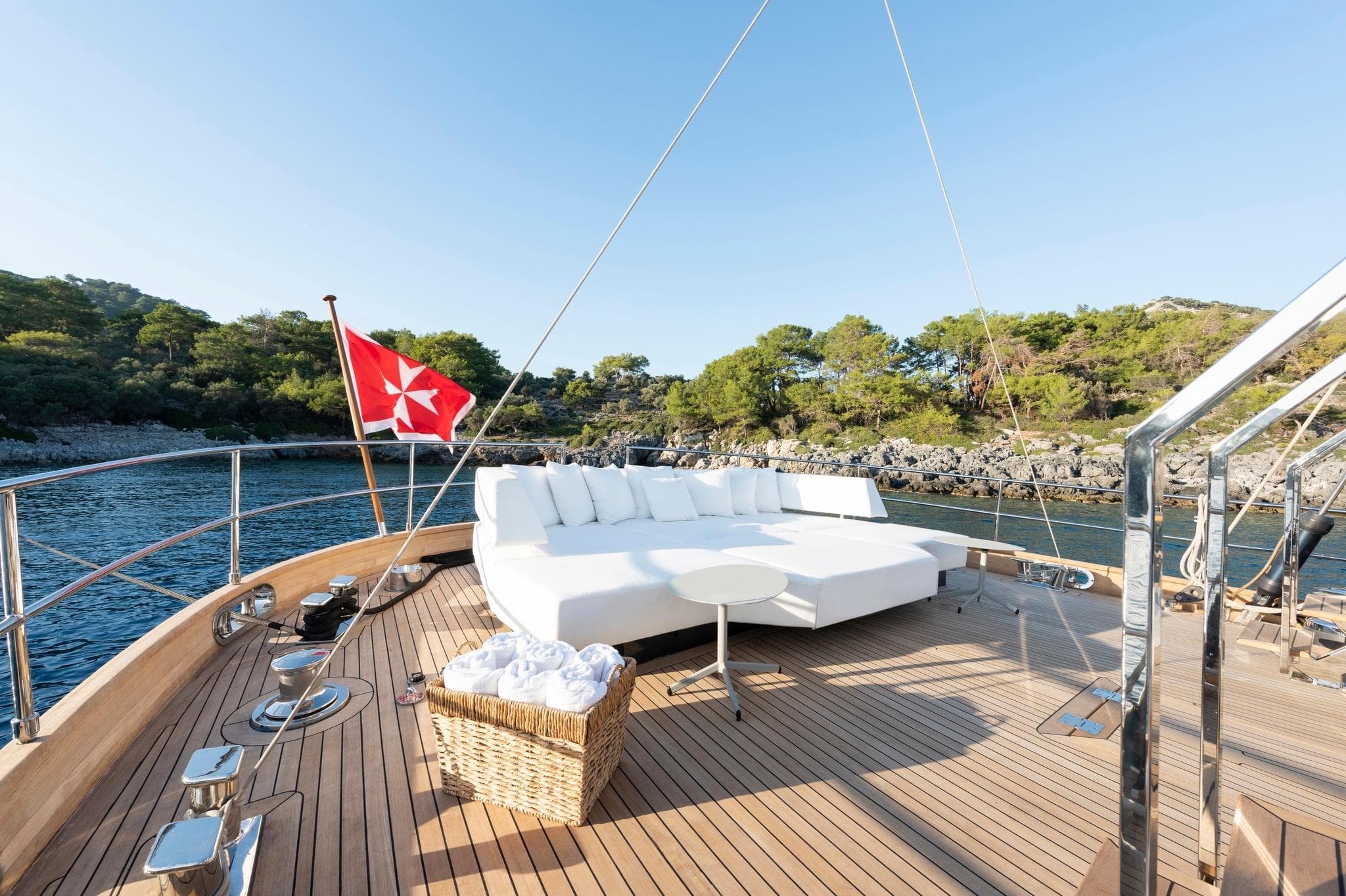 Luxurious 2013 CNT Castagnola Motorsailer deck with sunbed, scenic coastal view, and red flag.