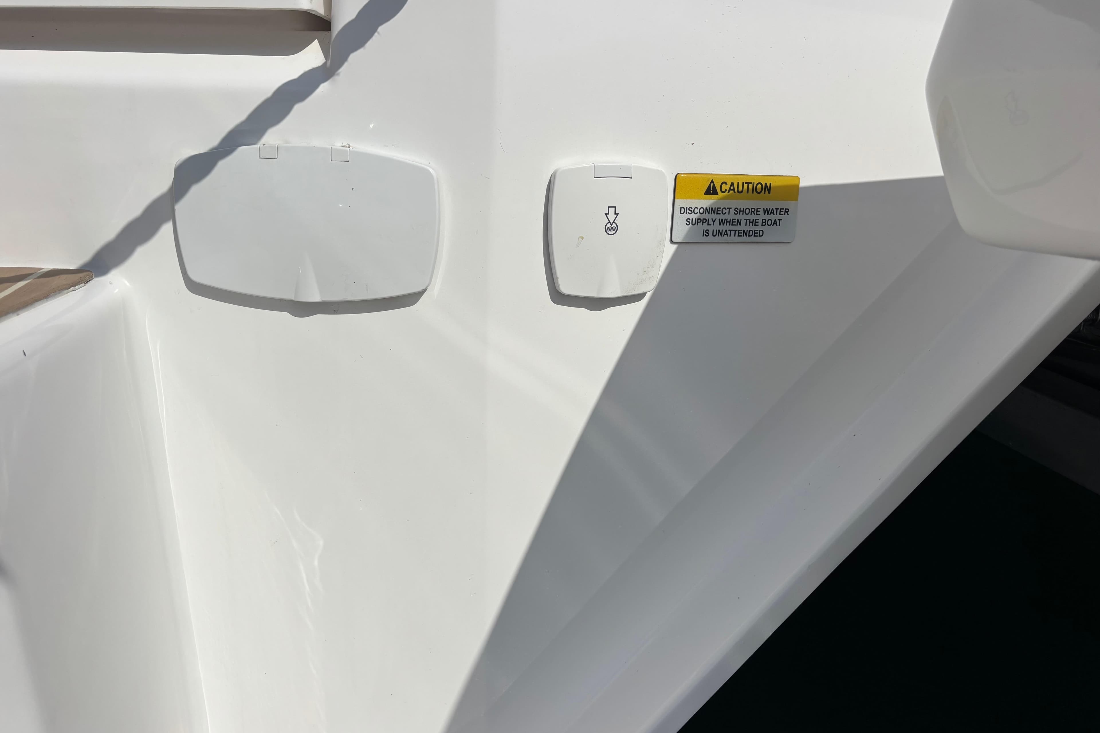 Close-up of a 2025 Leopard 52 boat's water connection and caution label.