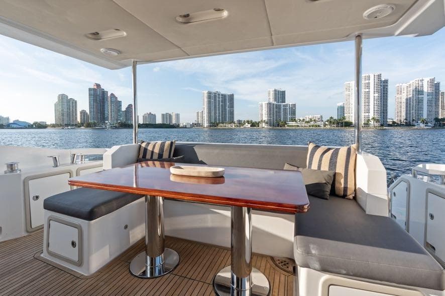 Luxurious Azimut 66 yacht deck with city skyline view, featuring elegant seating and table.