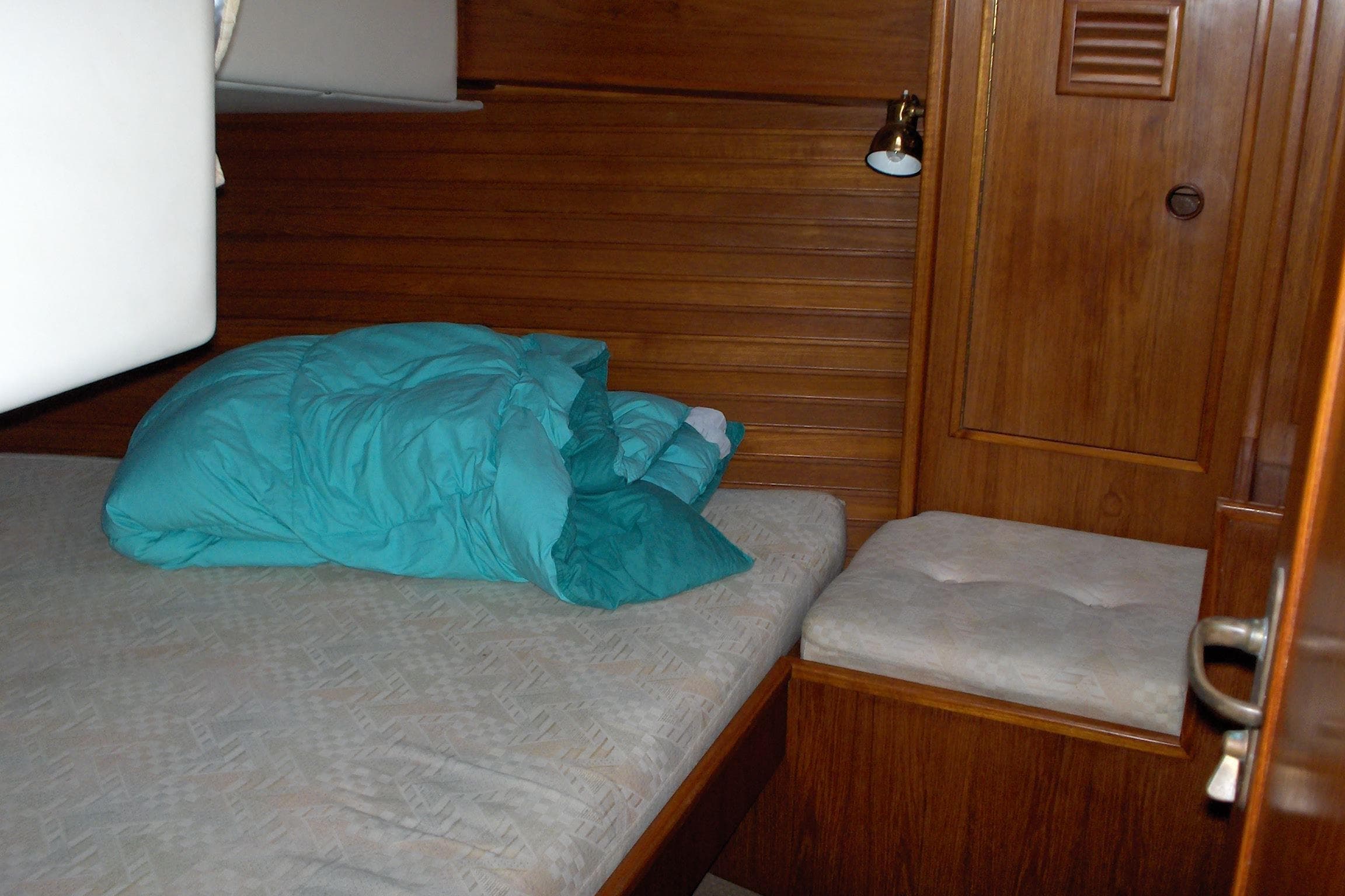 Cozy cabin interior of 1987 Wauquiez Centurion sailboat with teal bedding.