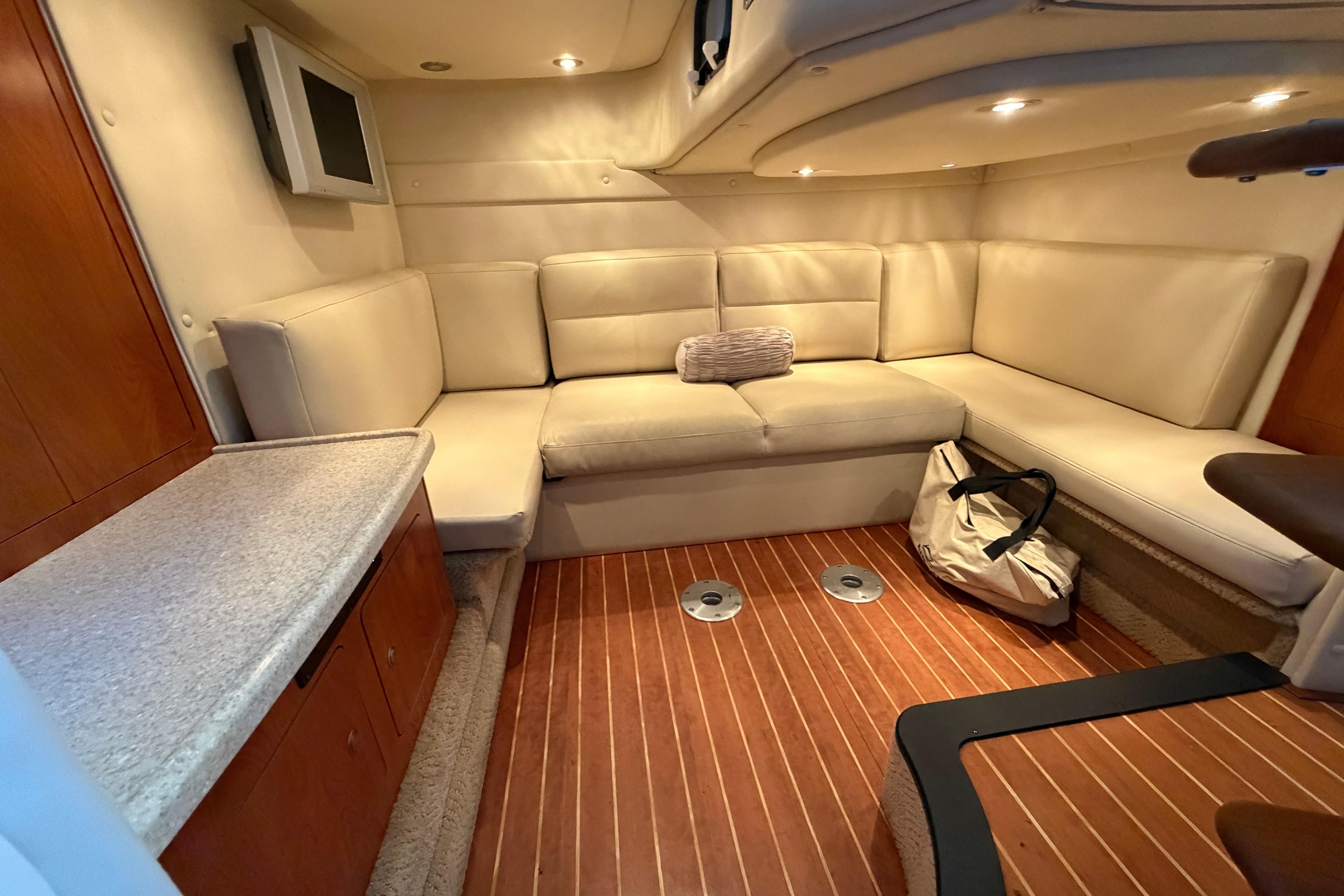 Interior of 2008 Rinker 350 Express Cruiser with beige seating and wood flooring.