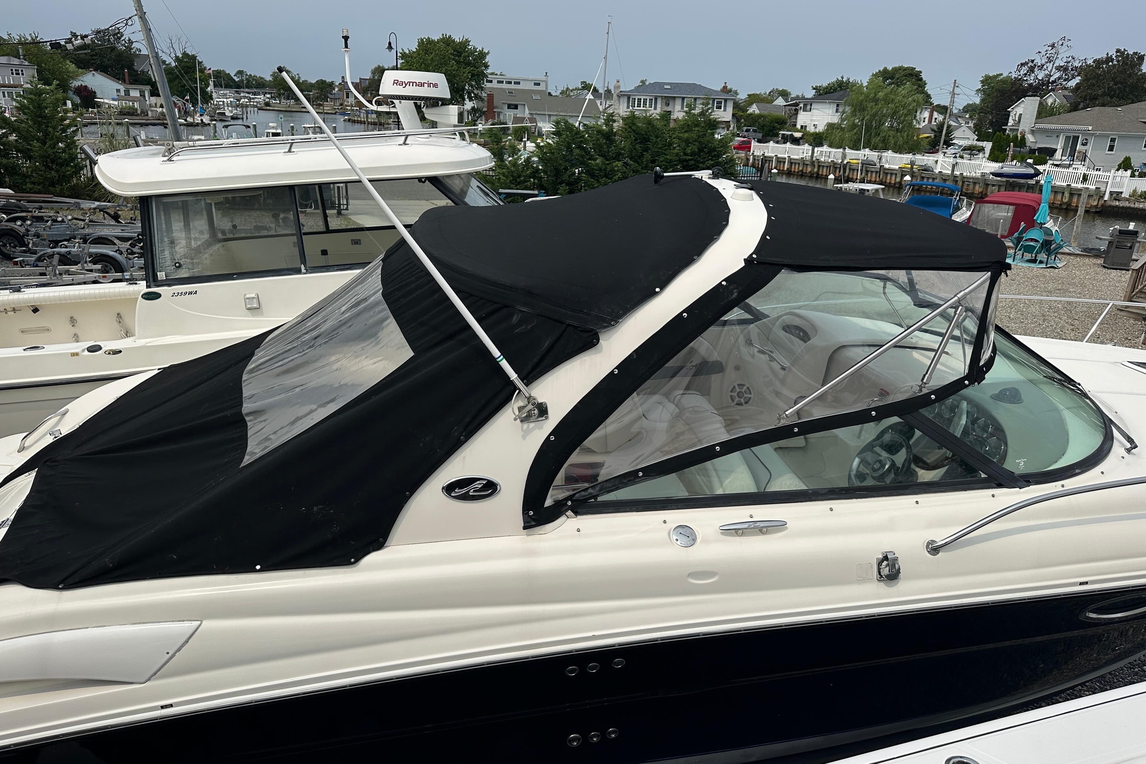 2005 Sea Ray 290 SLX boat with black canopy docked at marina.