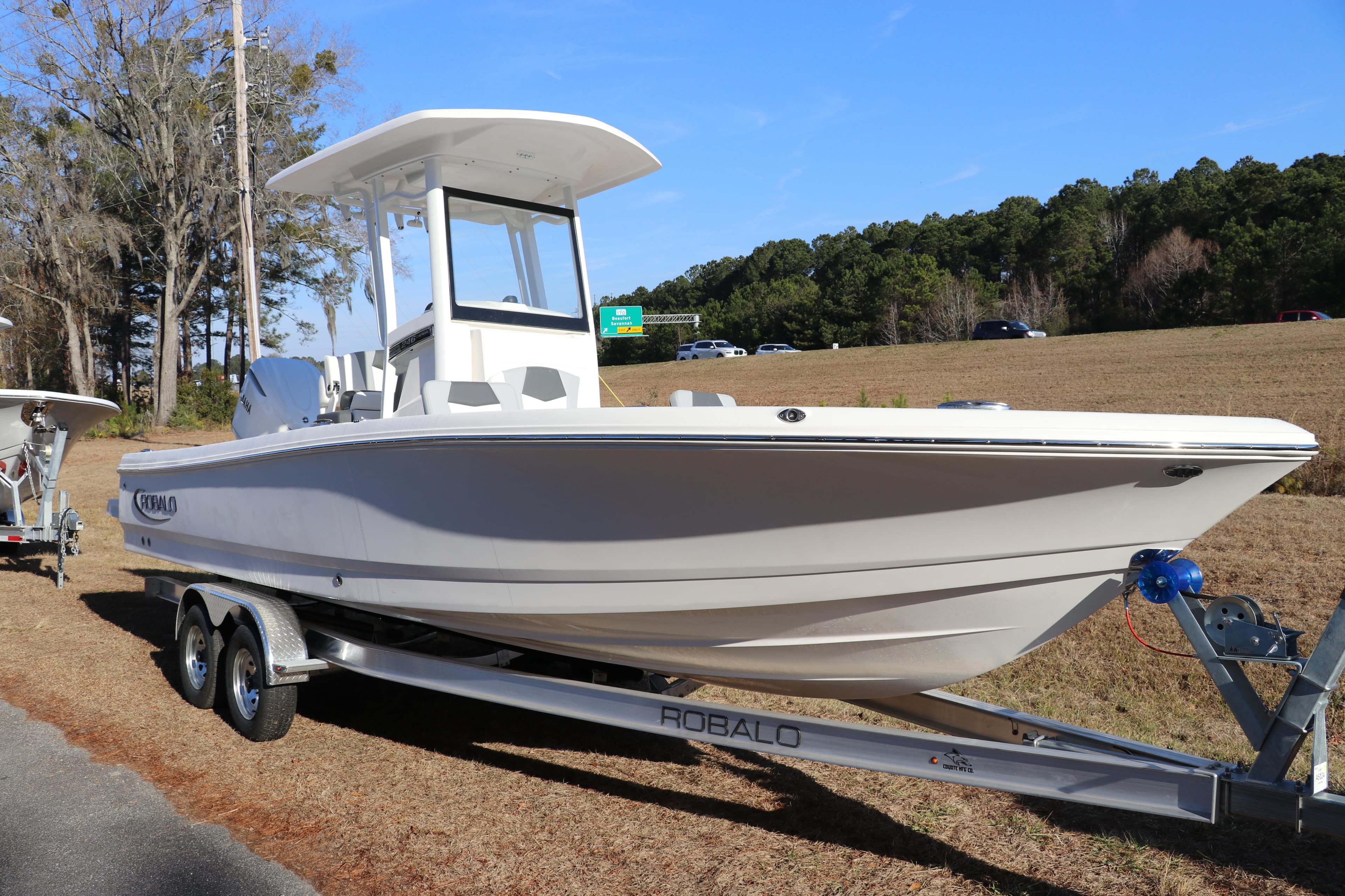 2026 Robalo 246 Cayman boat on trailer, parked outdoors, clear sky background.