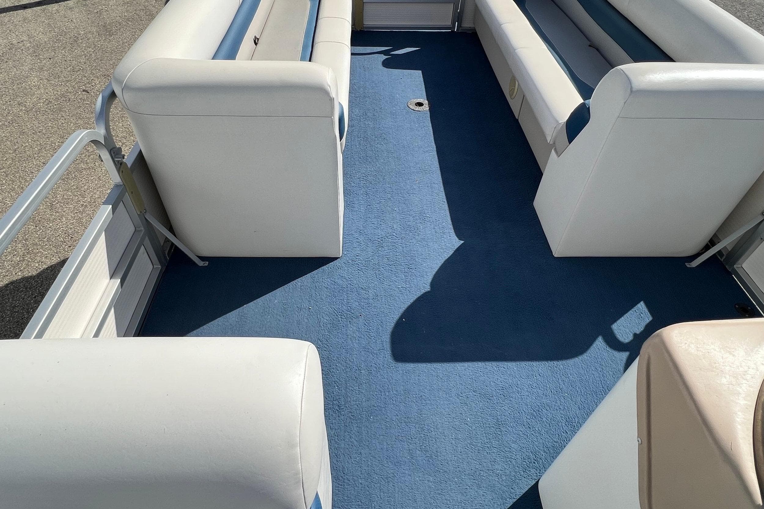 Interior of 2003 Sylvan 824 Mirage Cruise boat with blue carpet and white seating.
