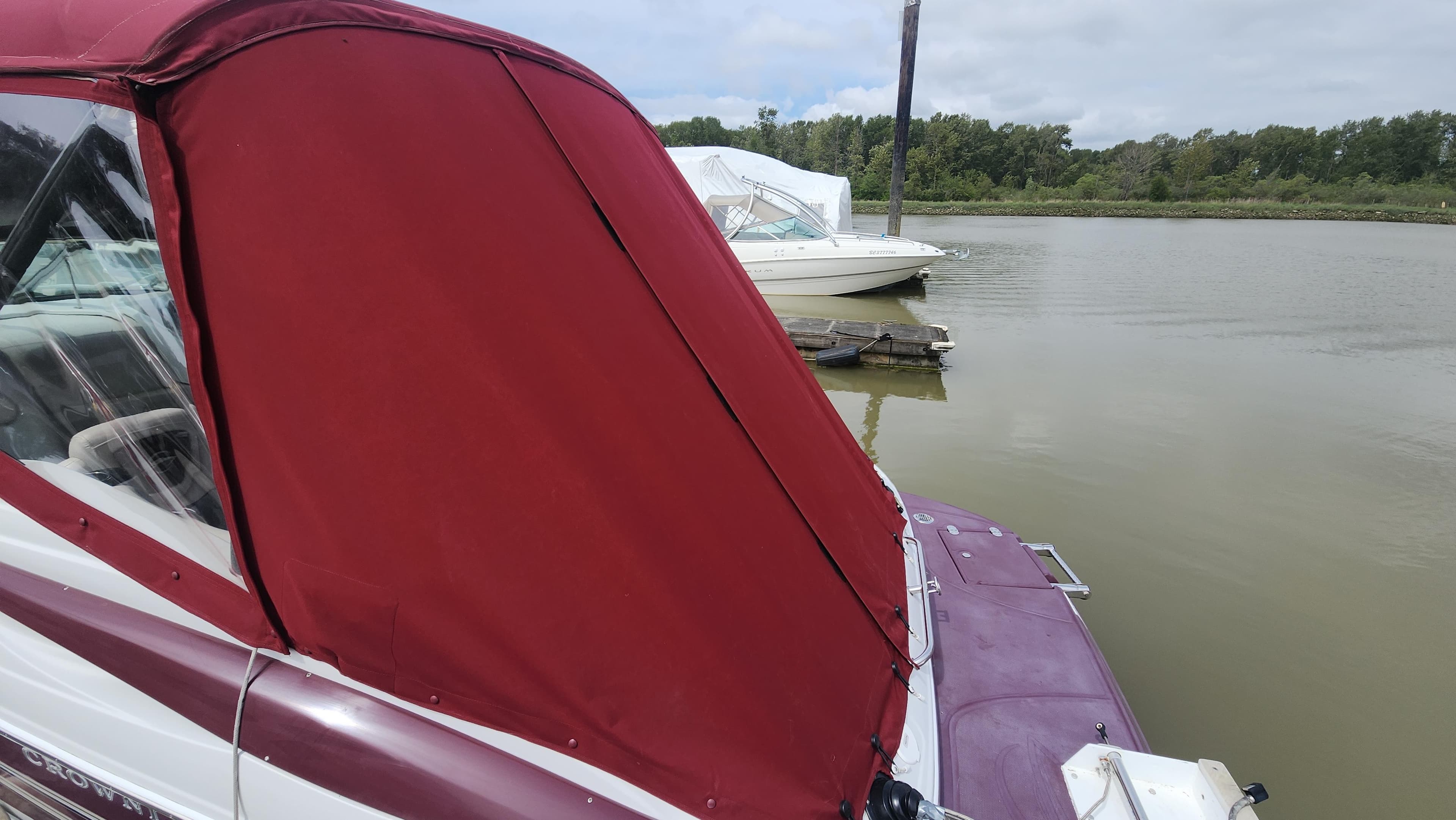 2008 Crownline 255 CCR boat with red cover docked on a calm lake.