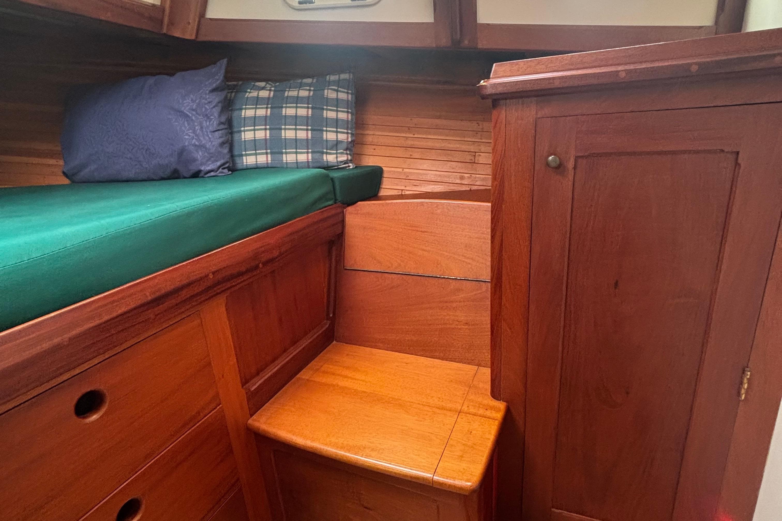 Cozy wooden boat cabin interior with green cushion and pillows, Lowell 40, 2001 model.