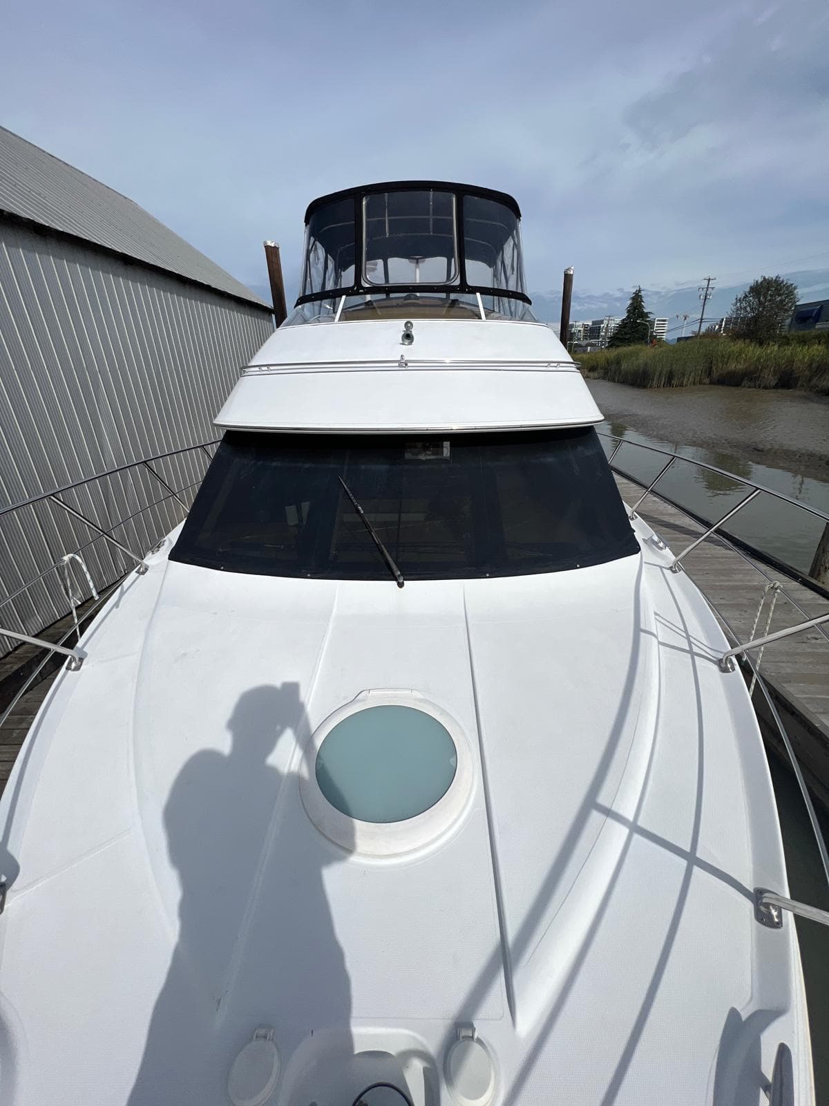 2003 Carver 360 Sport Sedan yacht docked near a metal building.