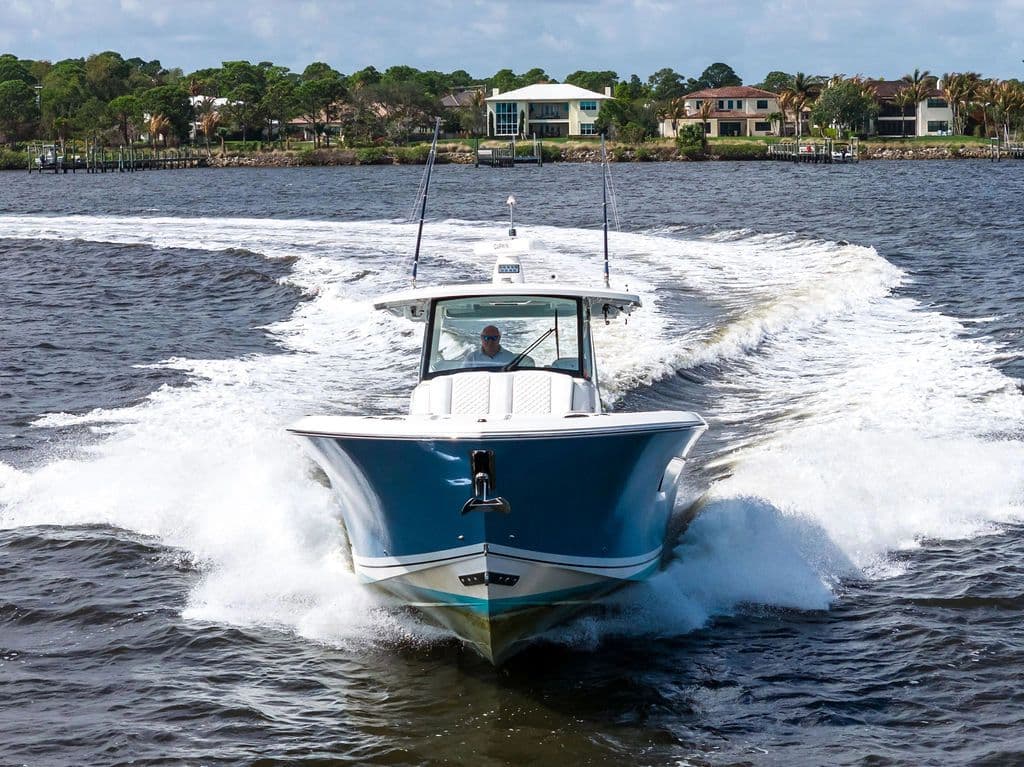 Pursuit S 378 Sport 2021 on water, coastal homes in background.