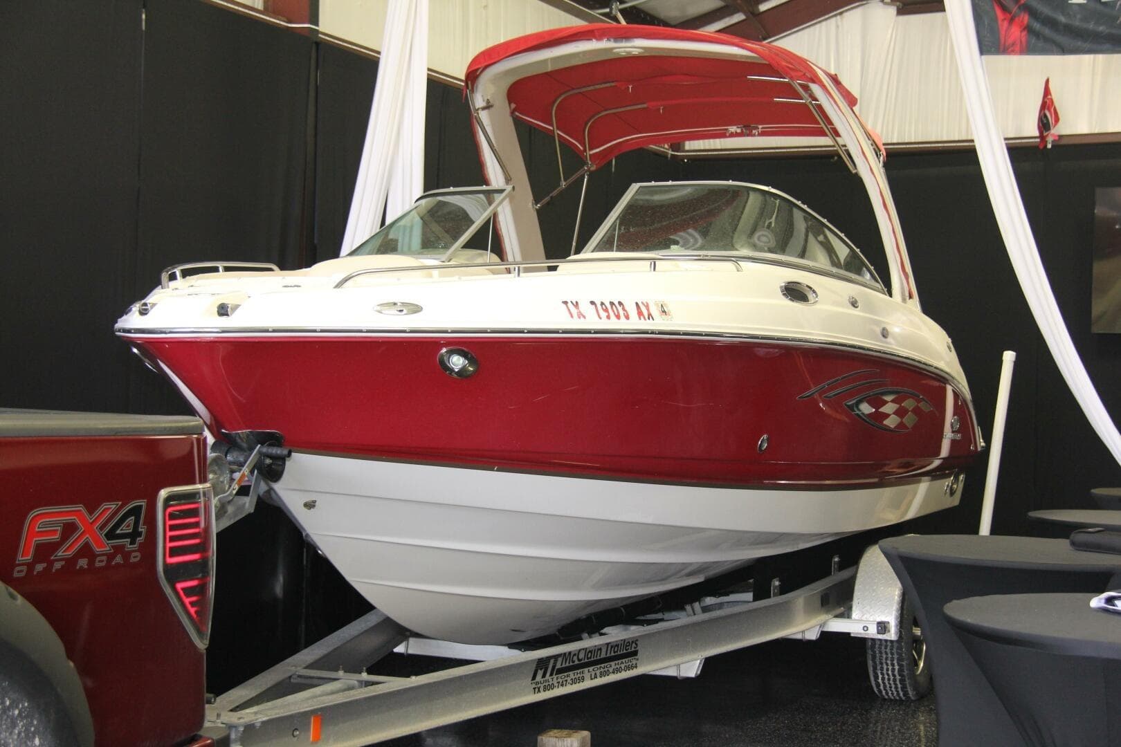2006 Chaparral 256 SSi boat with red and white design on a trailer indoors.