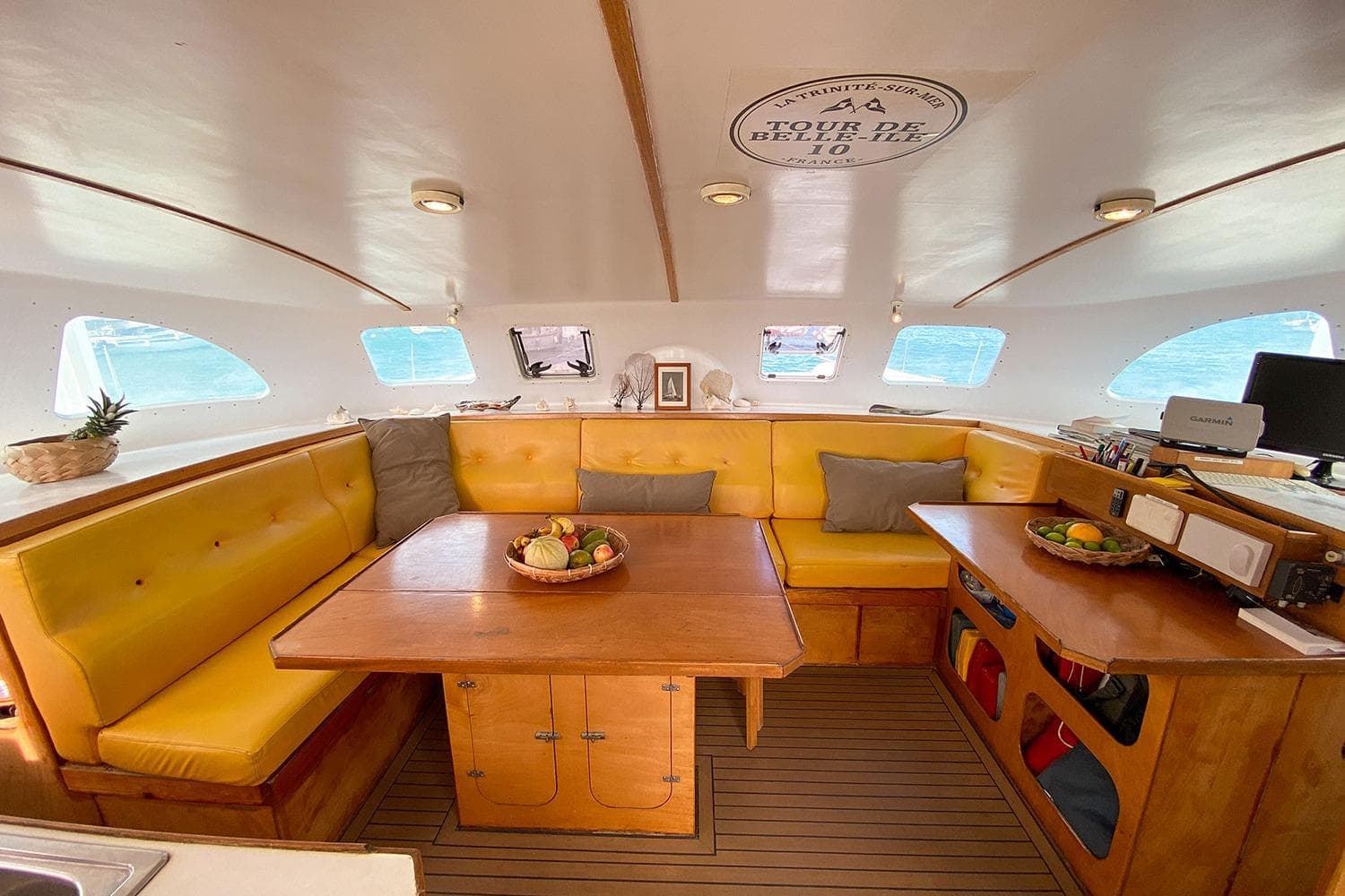 Cozy interior of 2004 BBL CAT 54 yacht with yellow seating and wooden table.