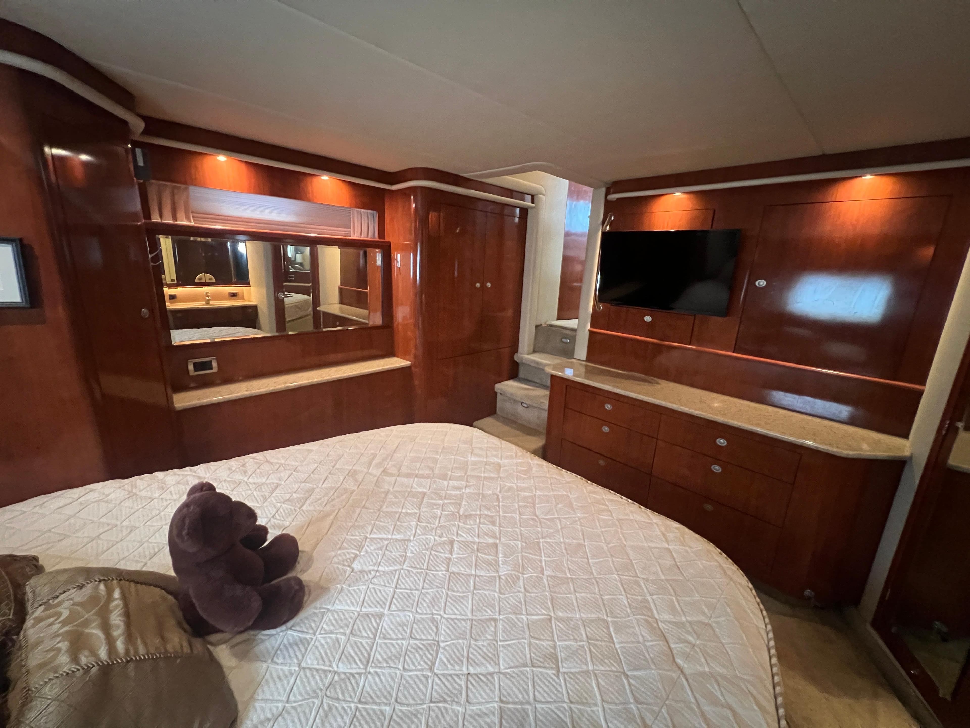 Luxurious 2004 Sea Ray 480 Motor Yacht bedroom with wood cabinetry and plush bedding.