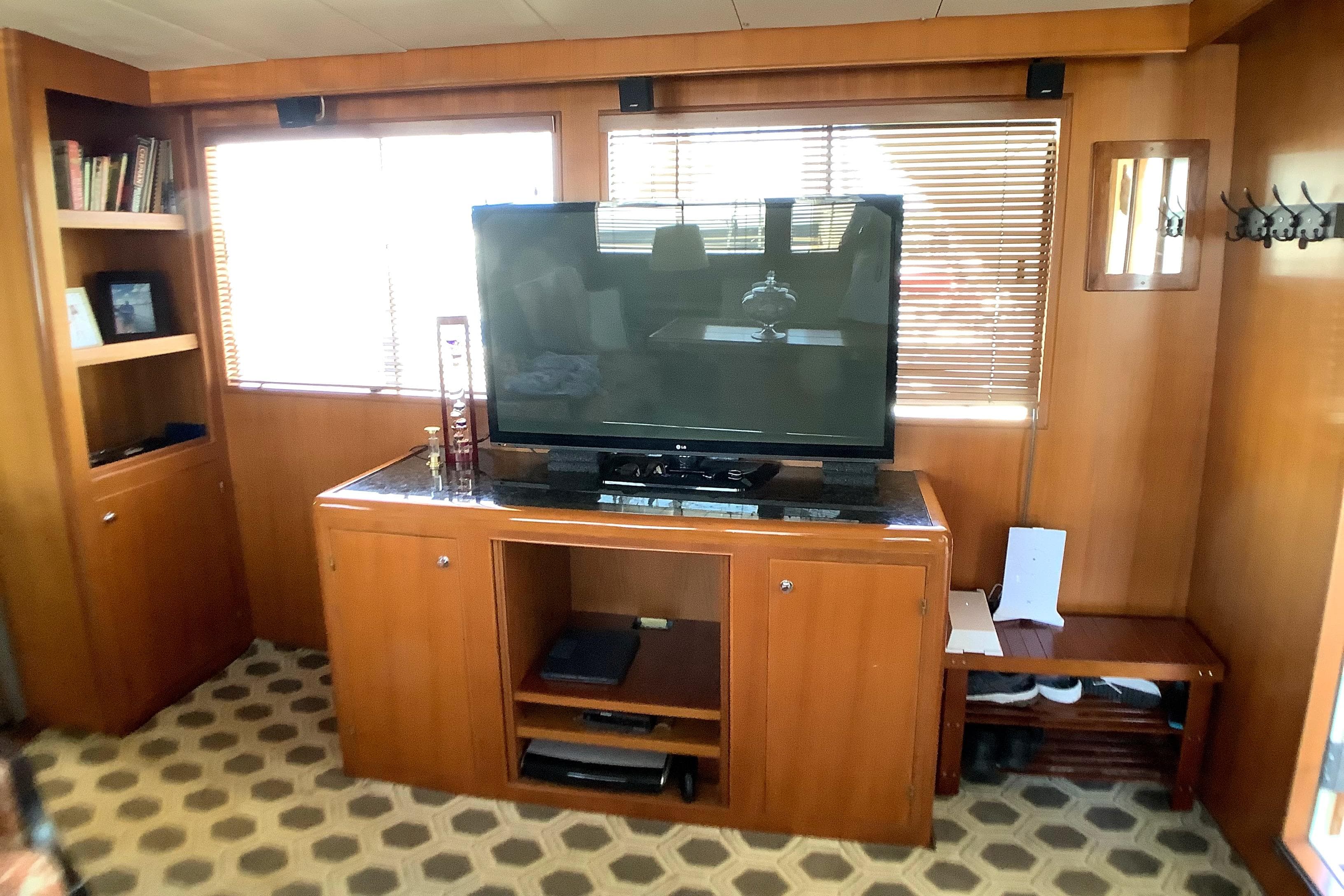 Interior of 1998 Grand Alaskan 60 Pilothouse with TV, wooden cabinetry, and patterned flooring.