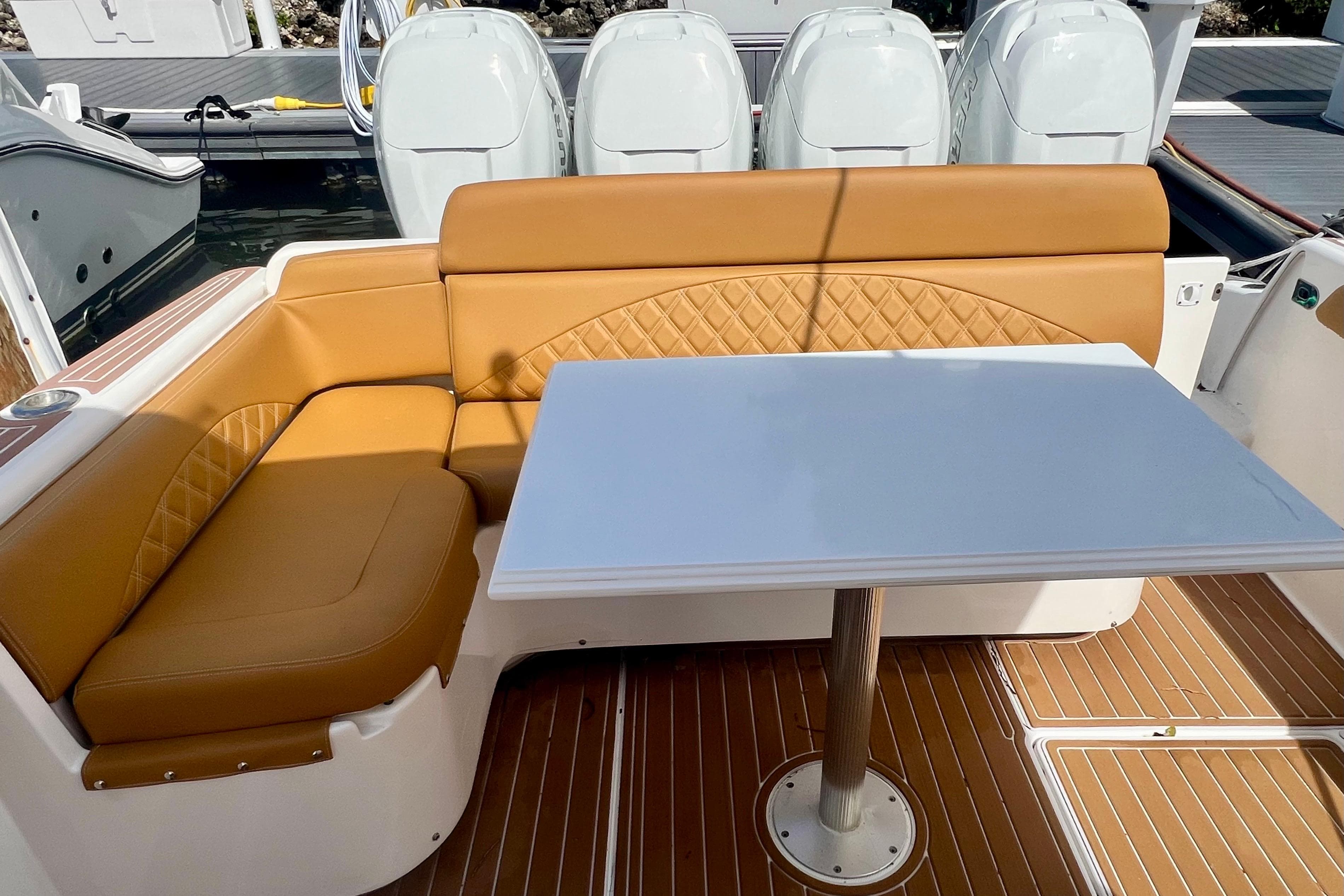 Luxurious seating area on 2011 Deep Impact 36 Open boat with tan upholstery and white table.