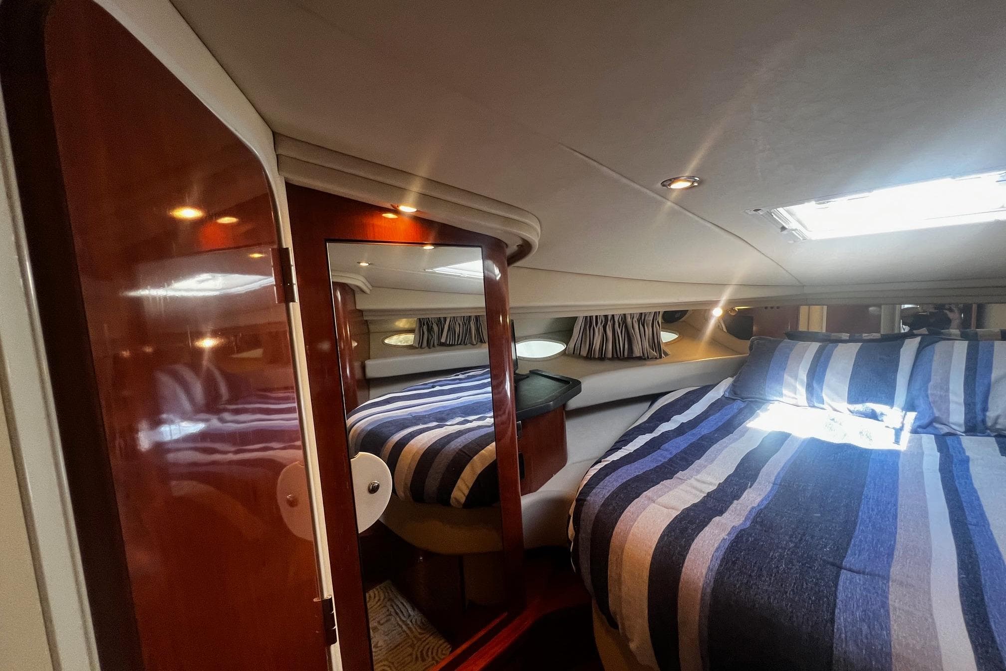 Luxurious cabin interior of 2003 Sea Ray 410 Express Cruiser with striped bedding.