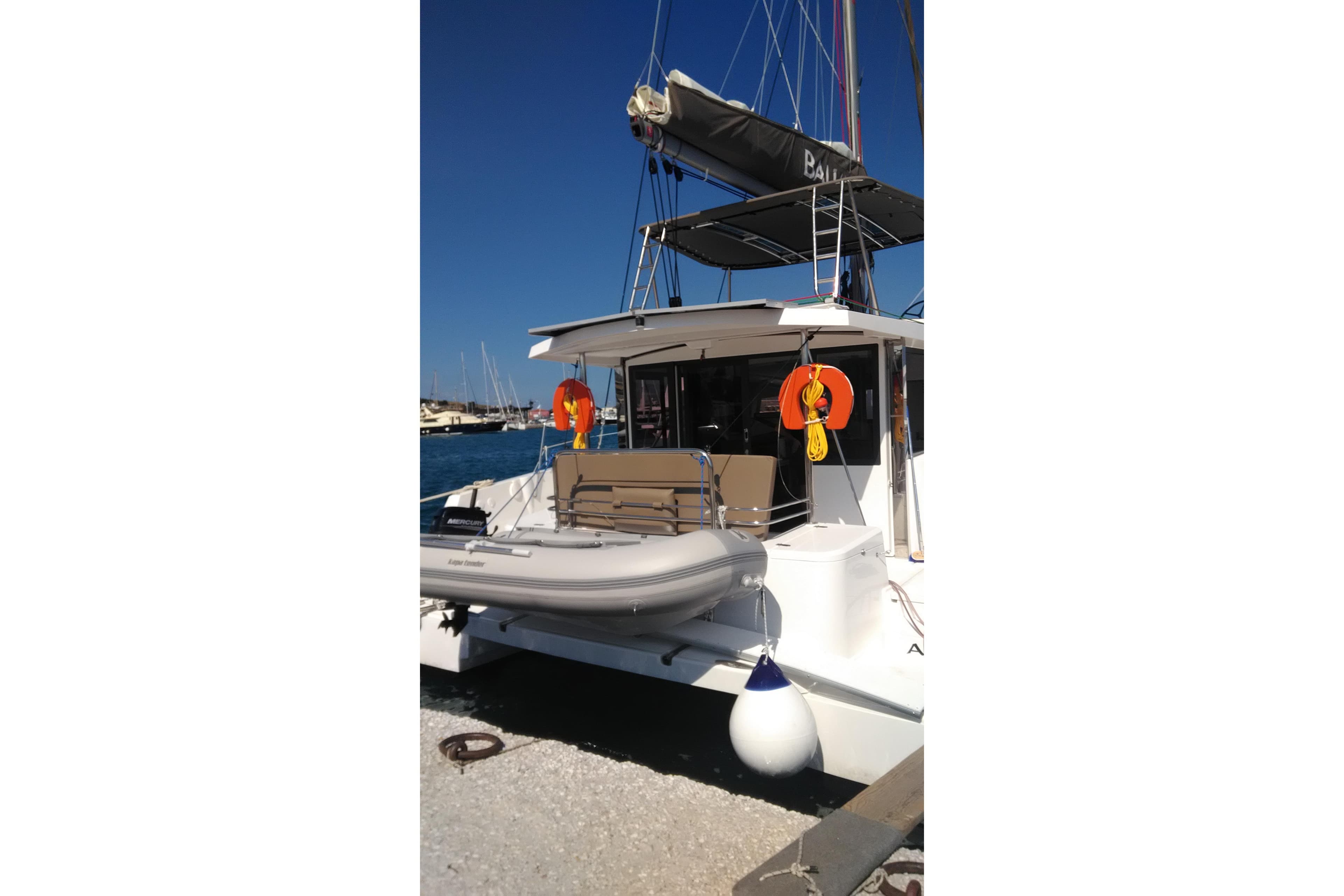 2018 Bali 4.1 catamaran docked, featuring lifebuoys and a small dinghy.