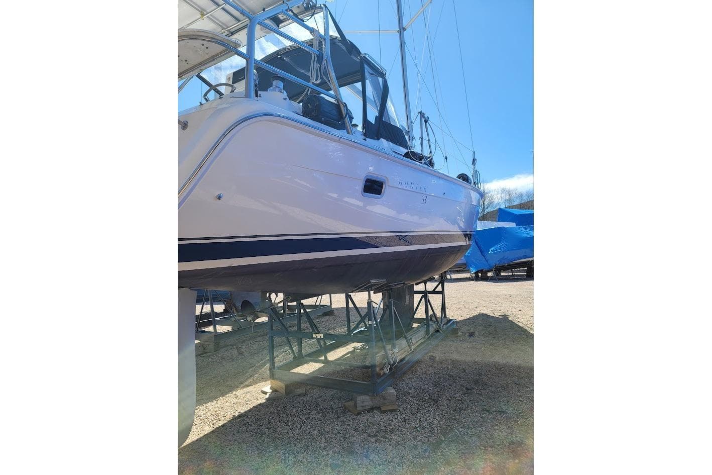2005 Hunter 33 sailboat on stands, viewed from the side, under clear blue sky.