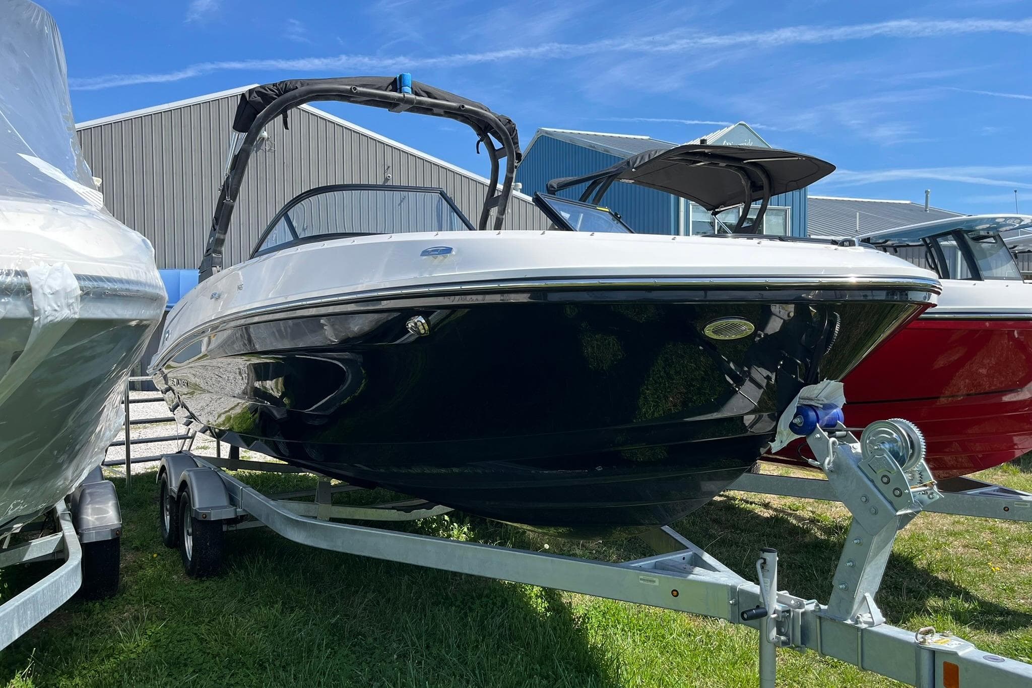 2026 Bayliner VR6 Bowrider OB on trailer, parked outdoors near other boats.