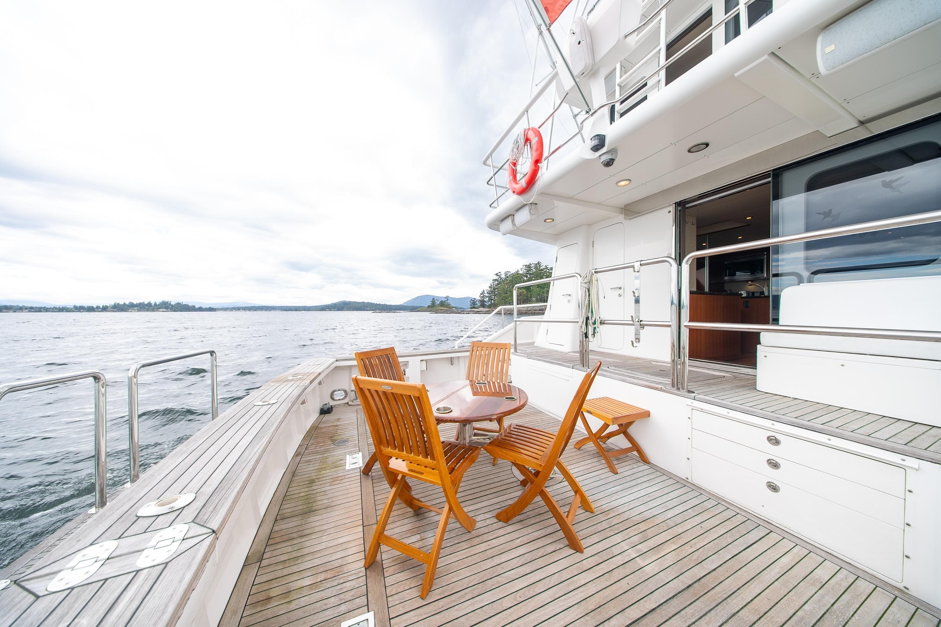 Deck of 2002 Striker 76 Sportfish Motor Yacht with wooden chairs and ocean view.