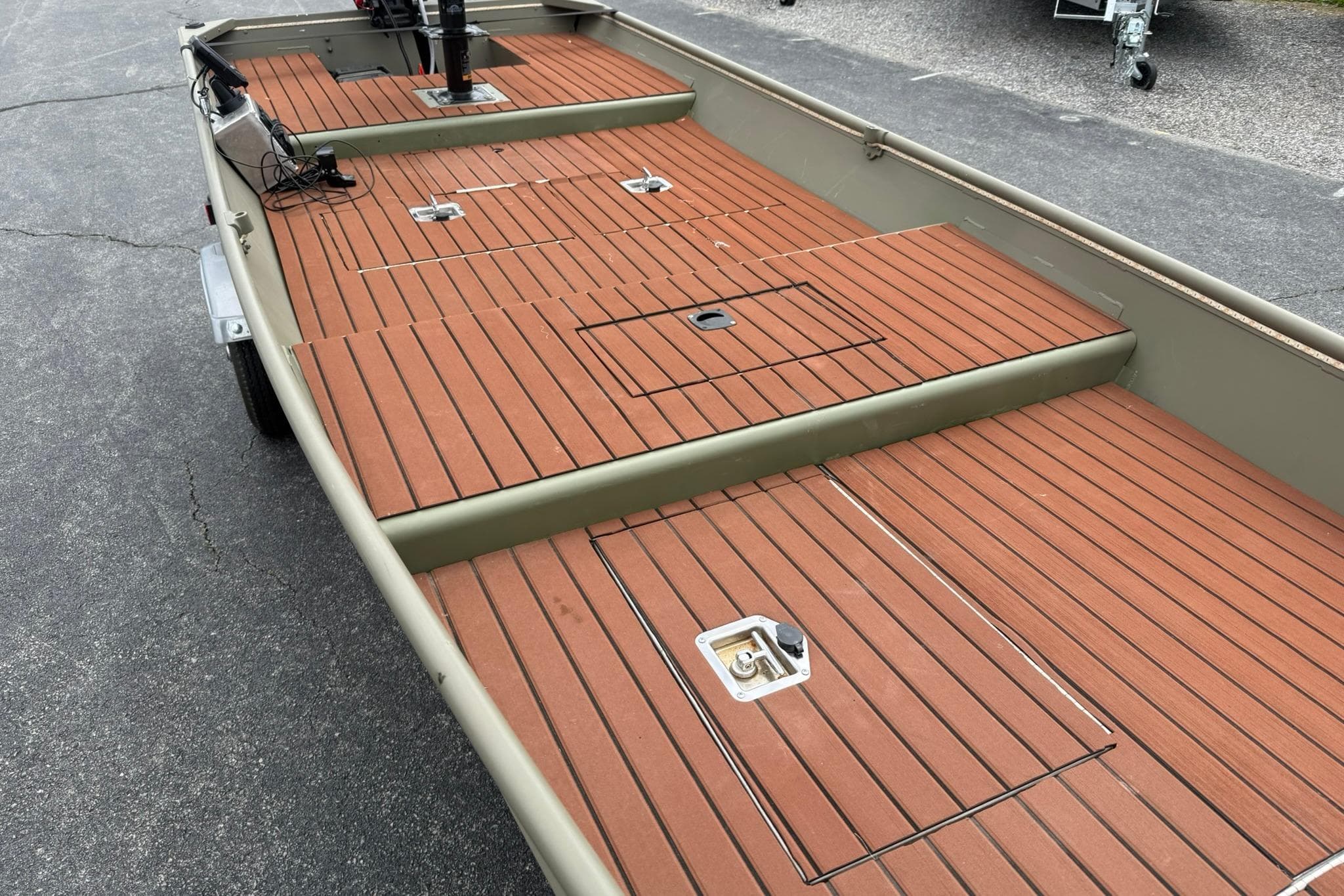 2025 Tracker Grizzly 1542 boat with wooden deck, parked on pavement.
