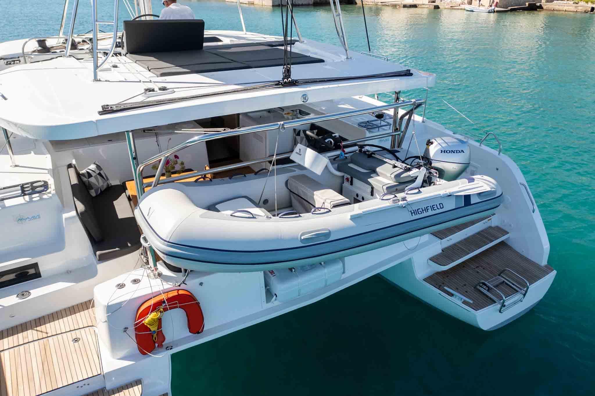2024 Lagoon 46 catamaran with dinghy, docked in clear turquoise water.