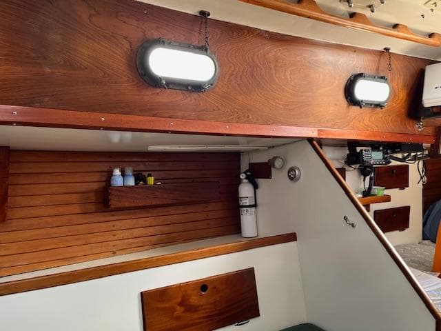 Interior of a 1979 Morris Leigh 30 sailboat with wooden paneling and porthole windows.