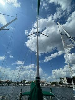 Sailboat mast of 2000 Beneteau Oceanis 311 against a bright blue sky with clouds.