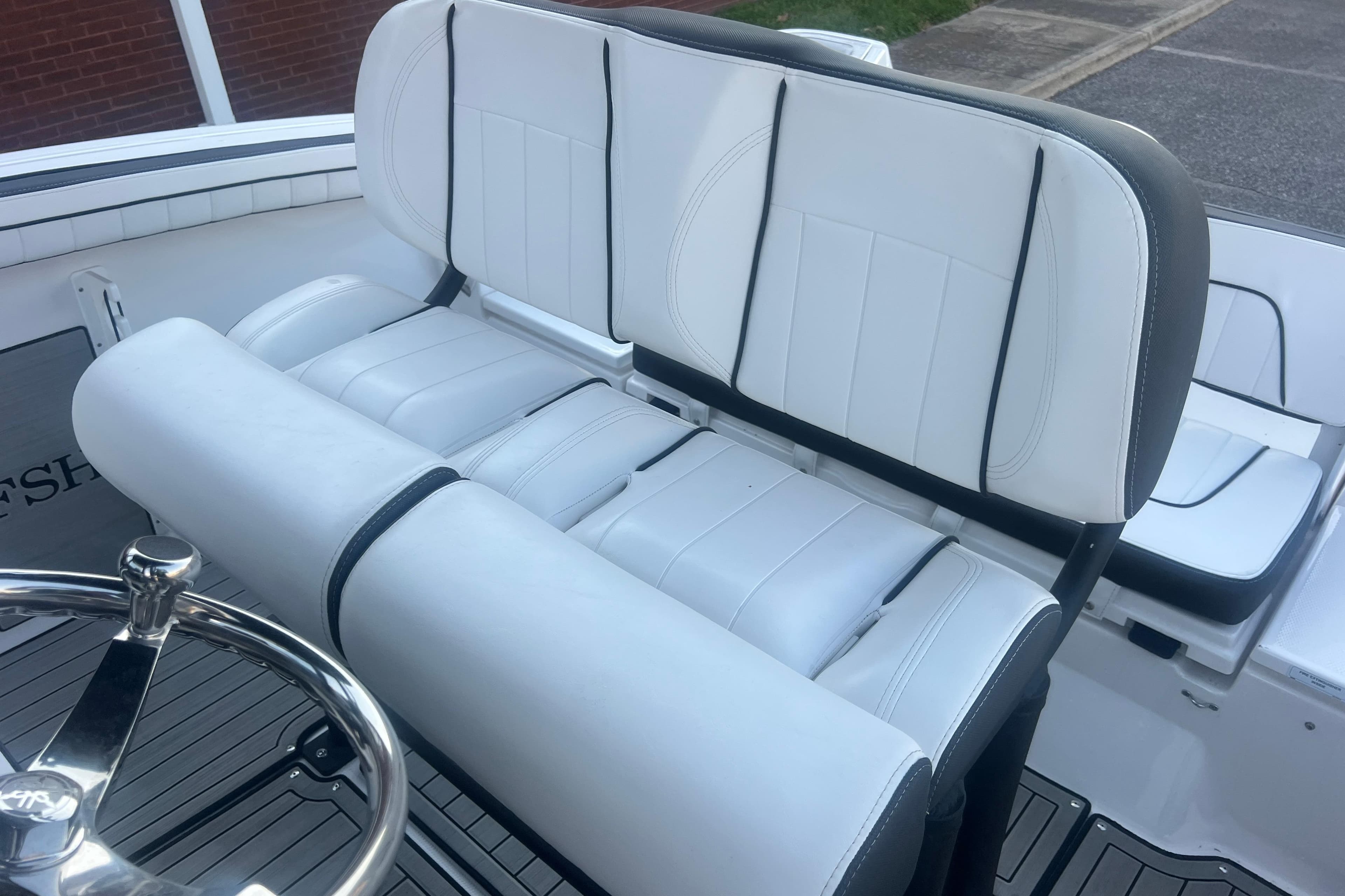 2024 Yamaha Boats 255 FSH Sport H interior seating with white upholstery and steering wheel.