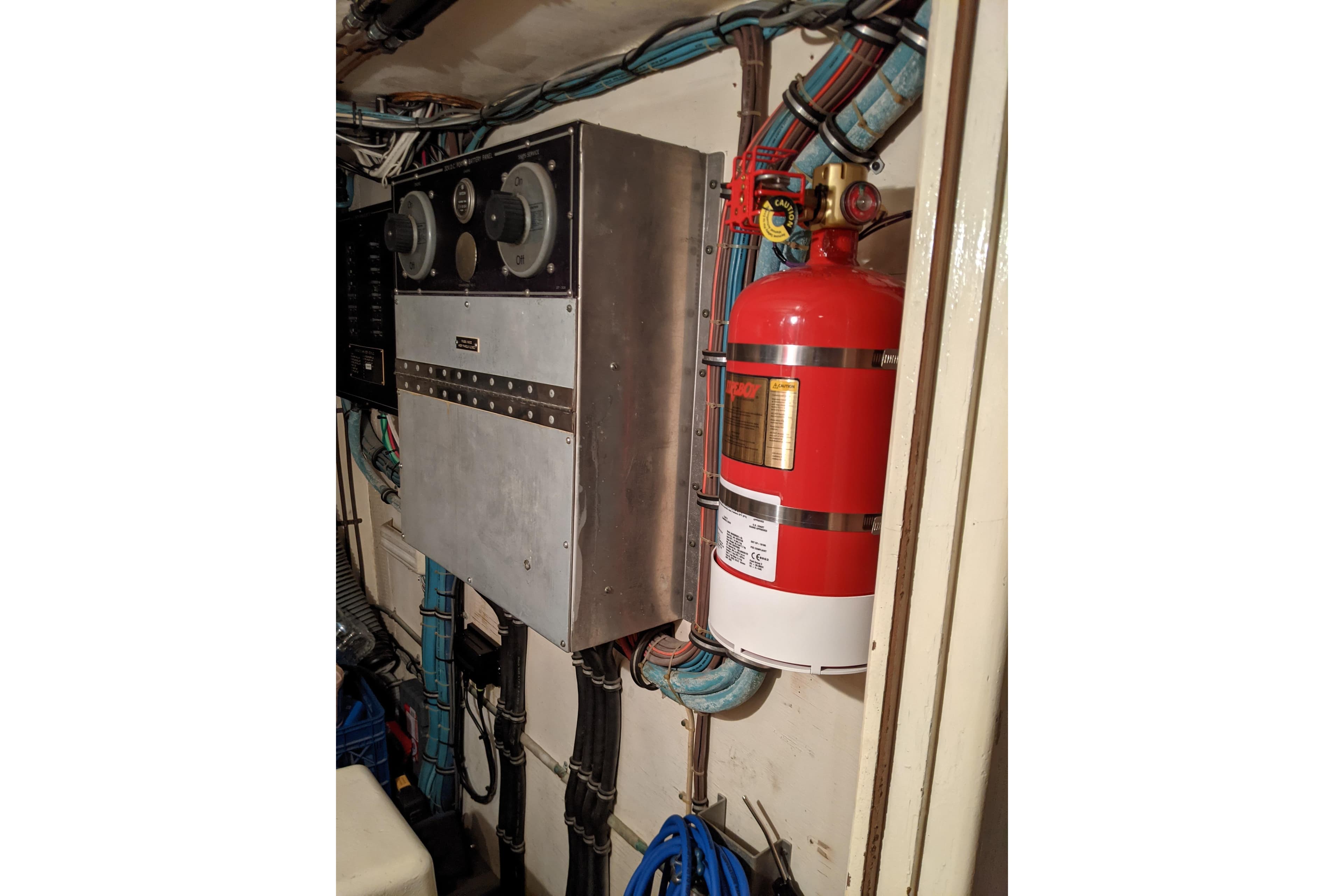 Engine room of 1984 Hatteras 53 Motor Yacht with fire extinguisher and control panel.