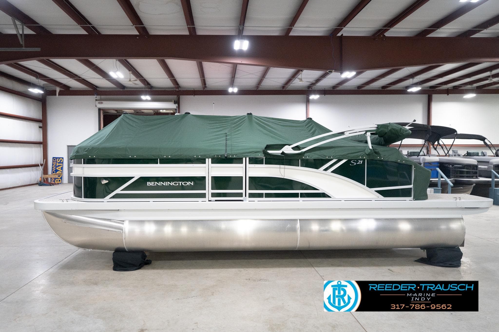 2026 Bennington 20 SLJ pontoon boat with green cover in indoor showroom.