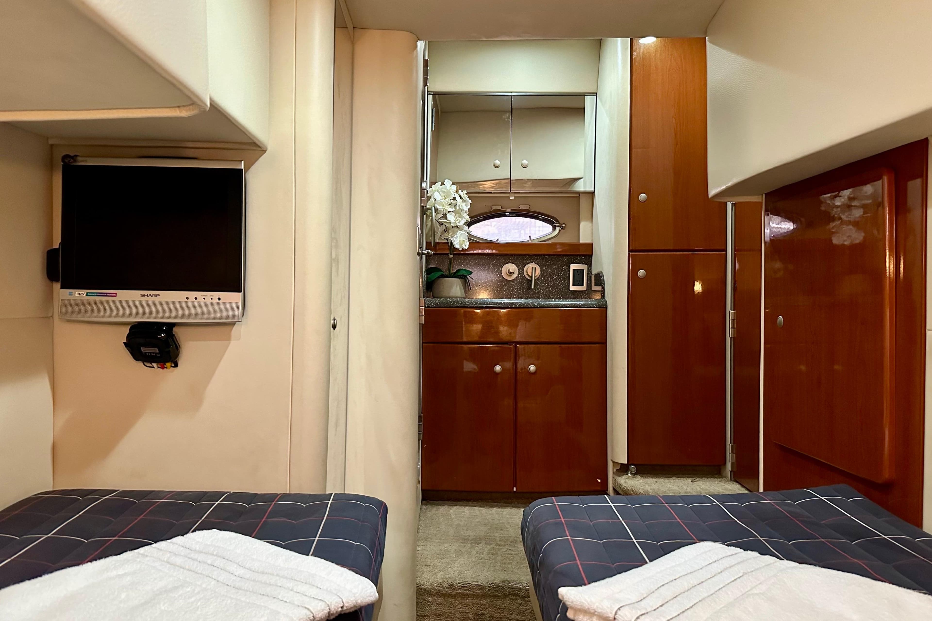 Interior of 2008 Formula 45 Yacht with twin beds, TV, and wooden cabinetry.