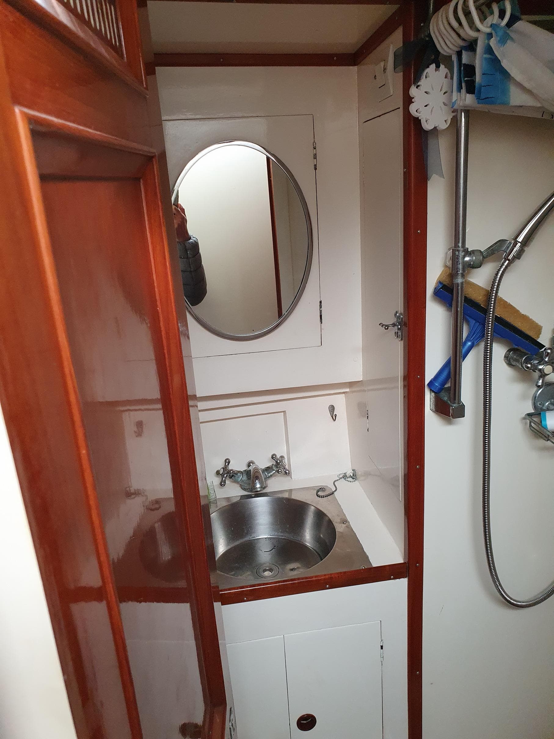 Classic 1933 Camper & Nicholsons ketch bathroom with sink, mirror, and wooden cabinetry.