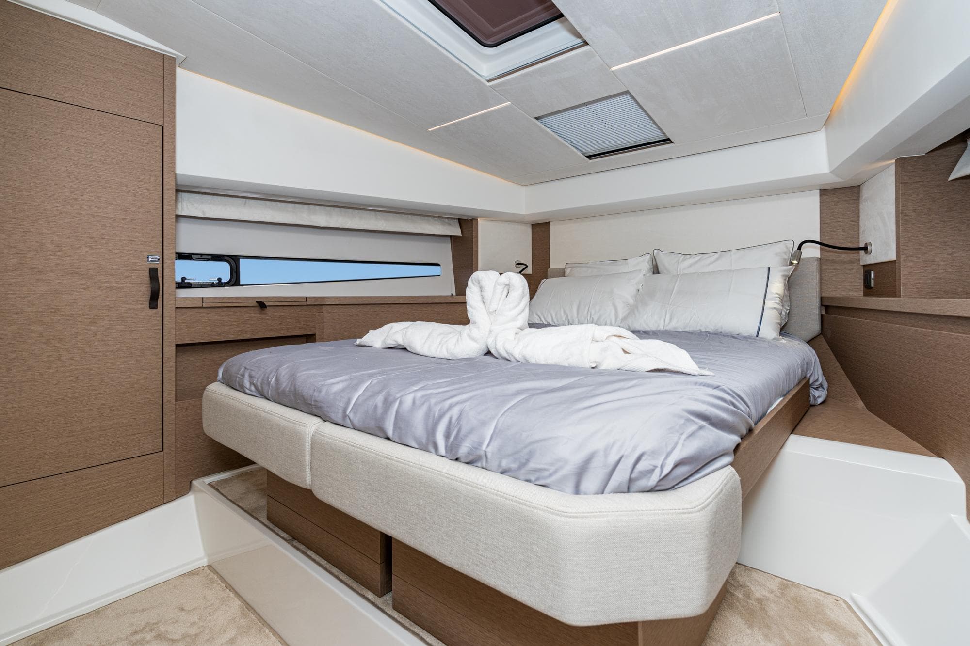 Luxurious bedroom interior of 2022 Prestige 460 yacht with modern design and skylight.