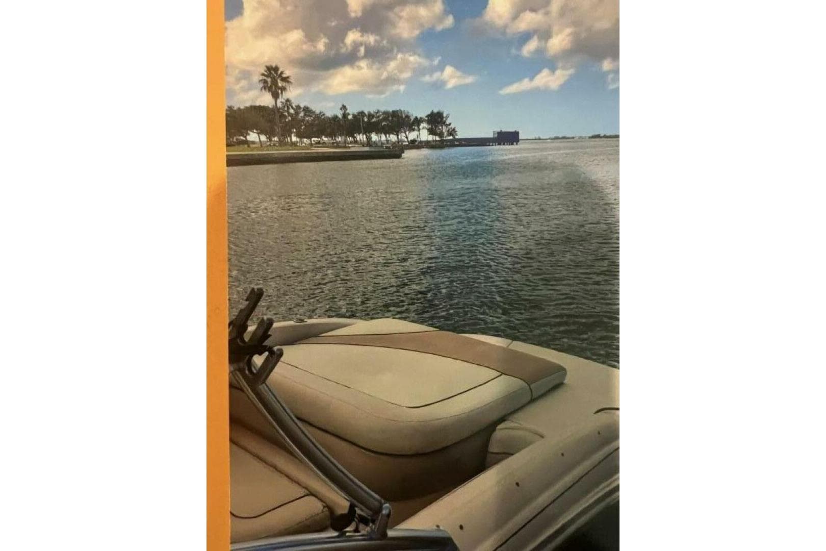 2003 Sea Ray 220 Bow Rider on tranquil water with scenic palm trees and cloudy sky.