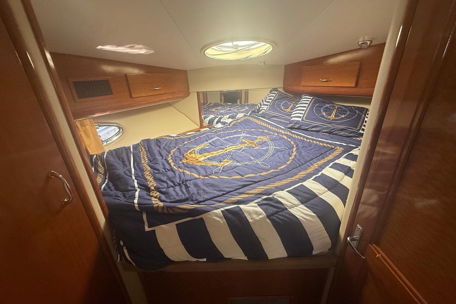 Cozy bedroom in 2004 Carver 396 Motor Yacht with nautical-themed bedding.