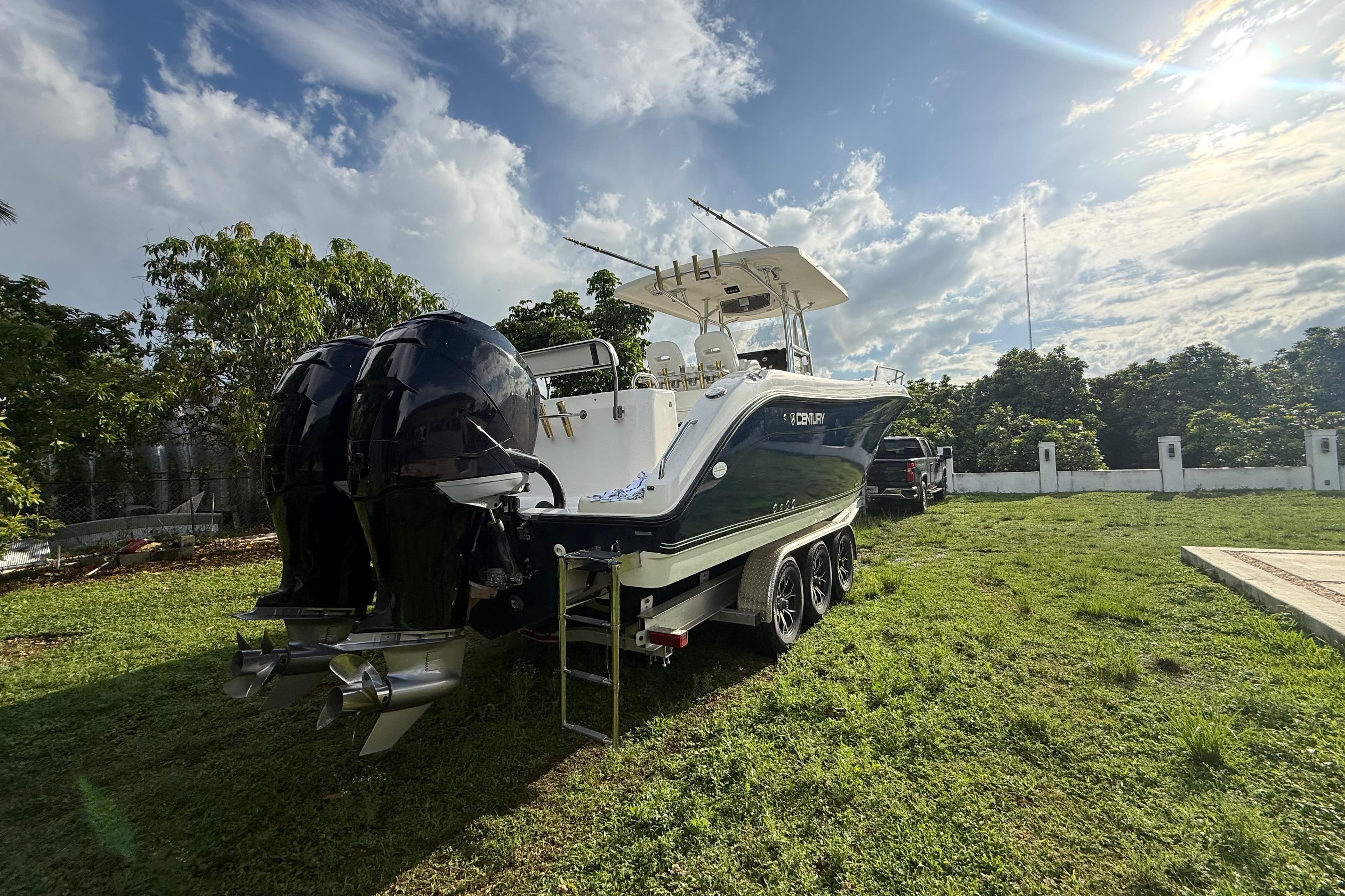 2007 Century 3200 Center Console boat on trailer, parked on grassy area under blue sky.