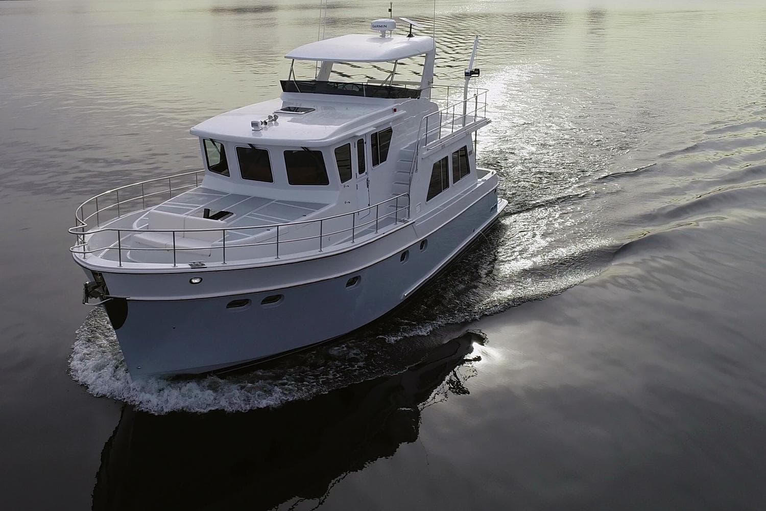 2026 Helmsman Trawlers 46 Pilothouse cruising on calm waters at sunset.