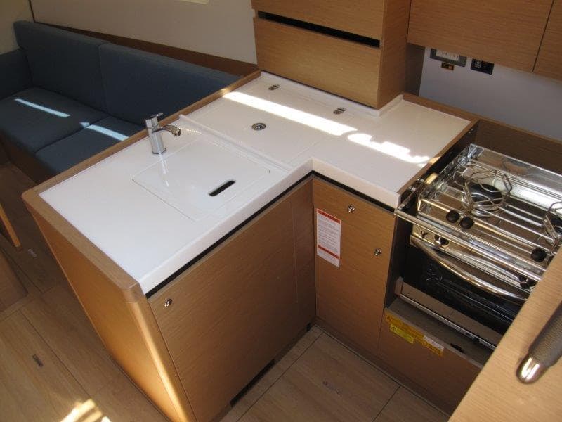 Modern kitchen in 2025 Jeanneau Sun Odyssey 350 yacht, featuring sleek countertops and stove.
