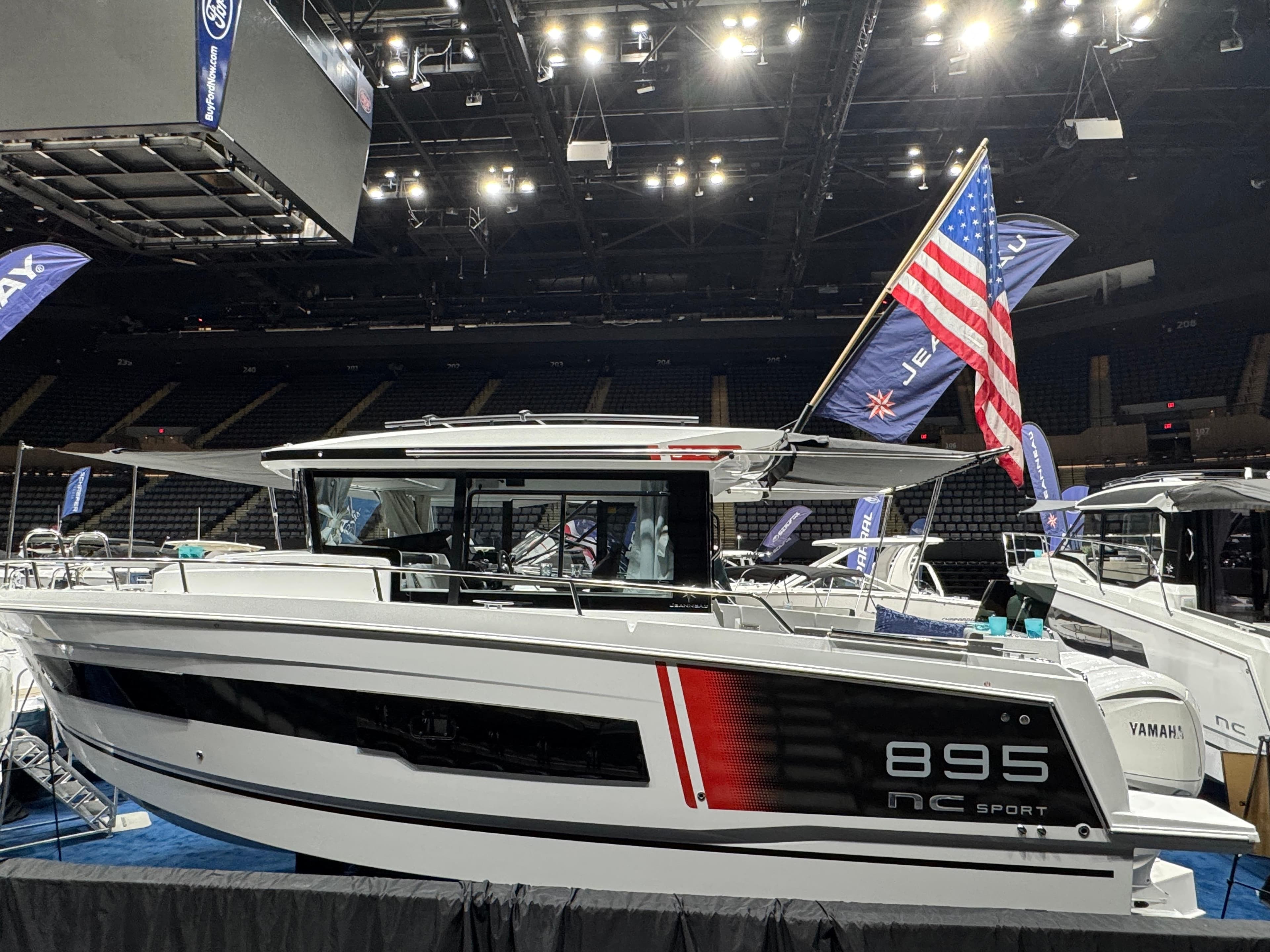 2025 Jeanneau NC 895 Sport Series 2 boat displayed indoors with flags.