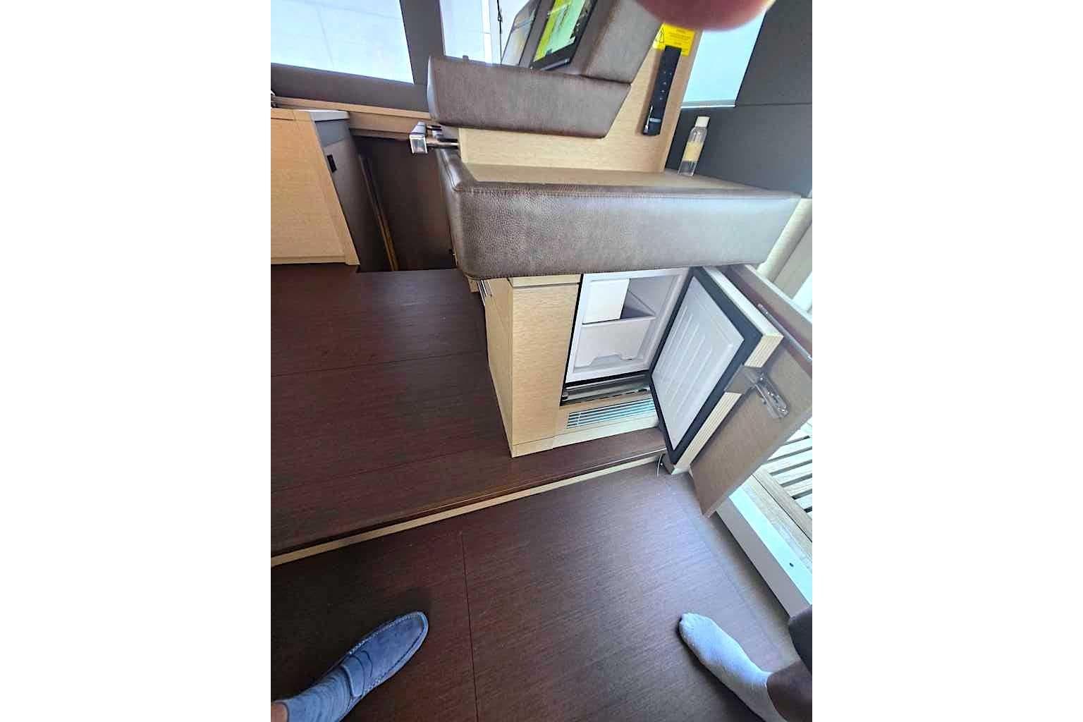 Interior of 2021 Lagoon SIXTY 7 yacht with open mini fridge and seating area.