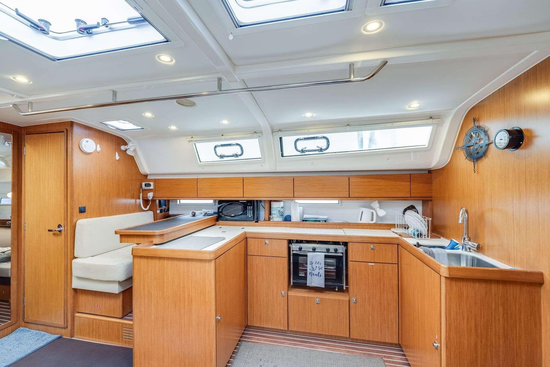 Interior of 2016 Bavaria 51 Cruiser yacht with modern kitchen and wooden cabinetry.
