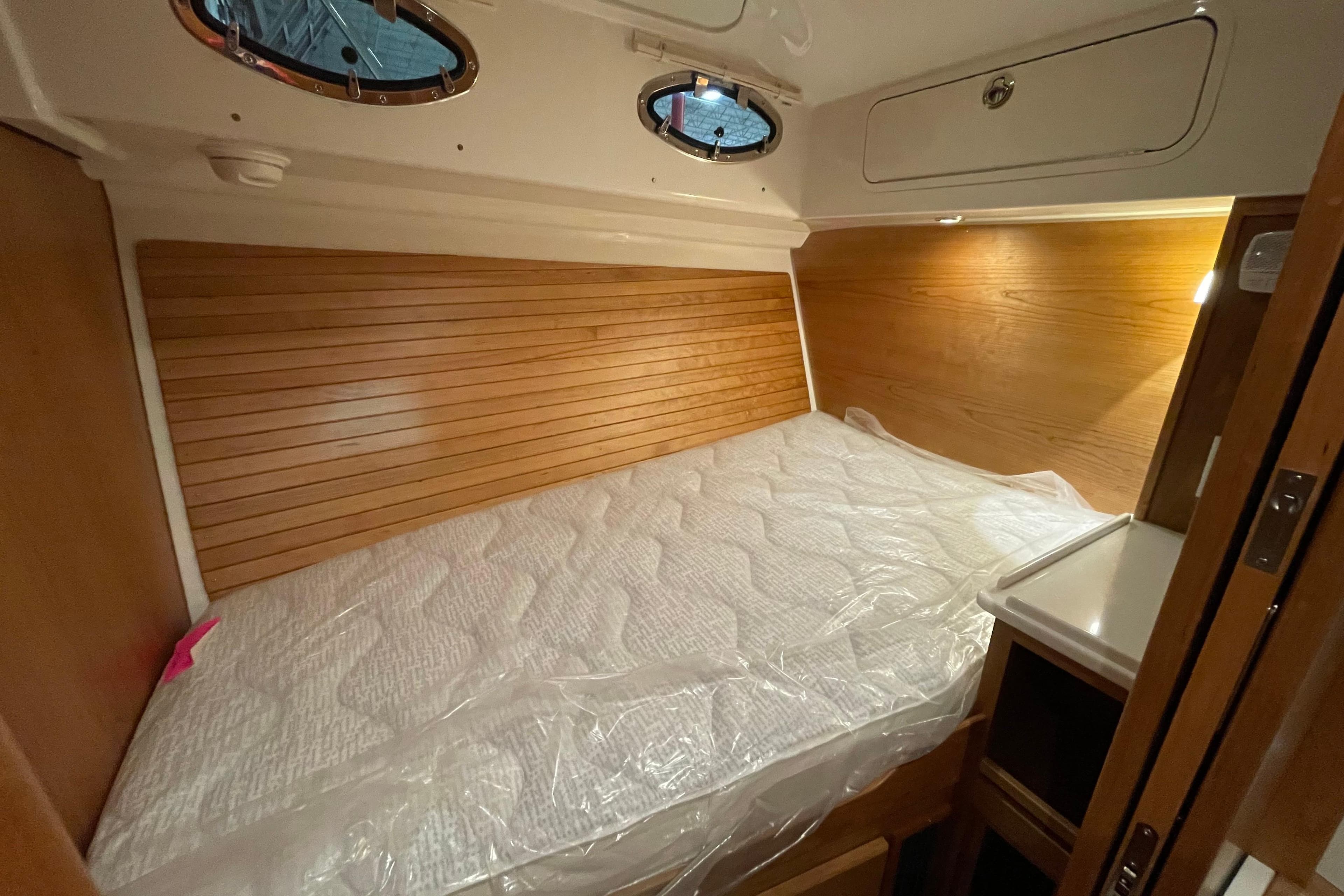 2026 Back Cove 372 cabin interior with wooden paneling and a neatly made bed.