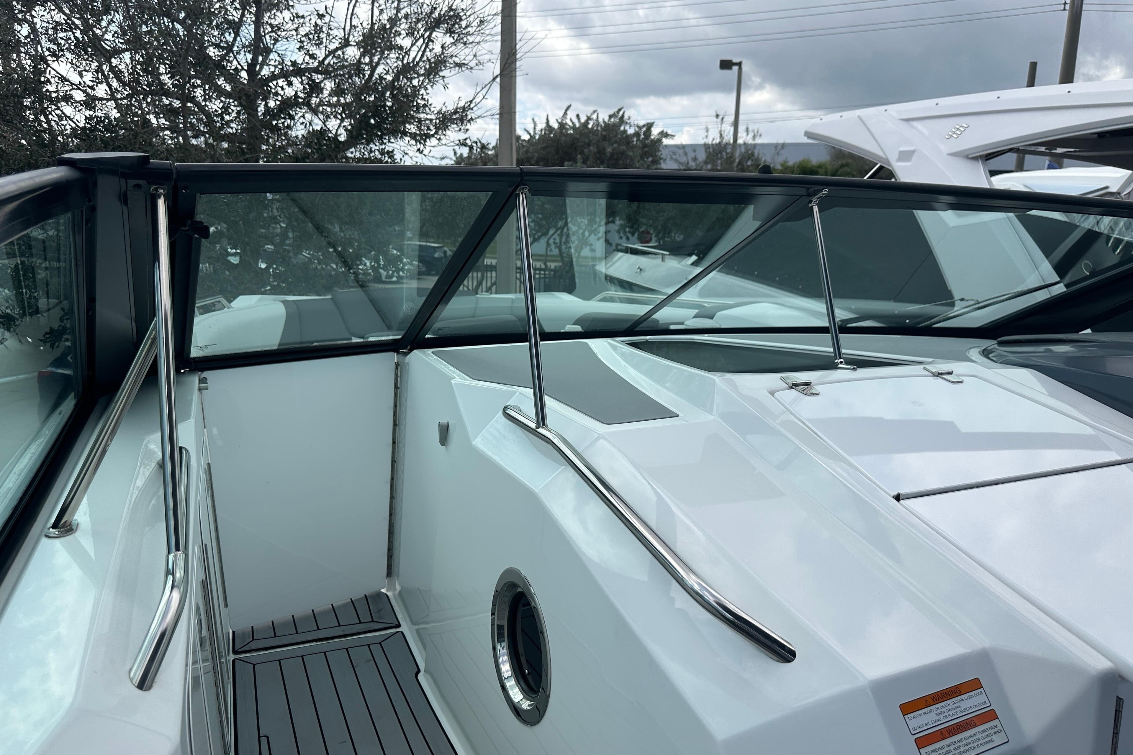 2019 Cruisers Yachts 338 Outboard, sleek white deck with glass railing, overcast sky.