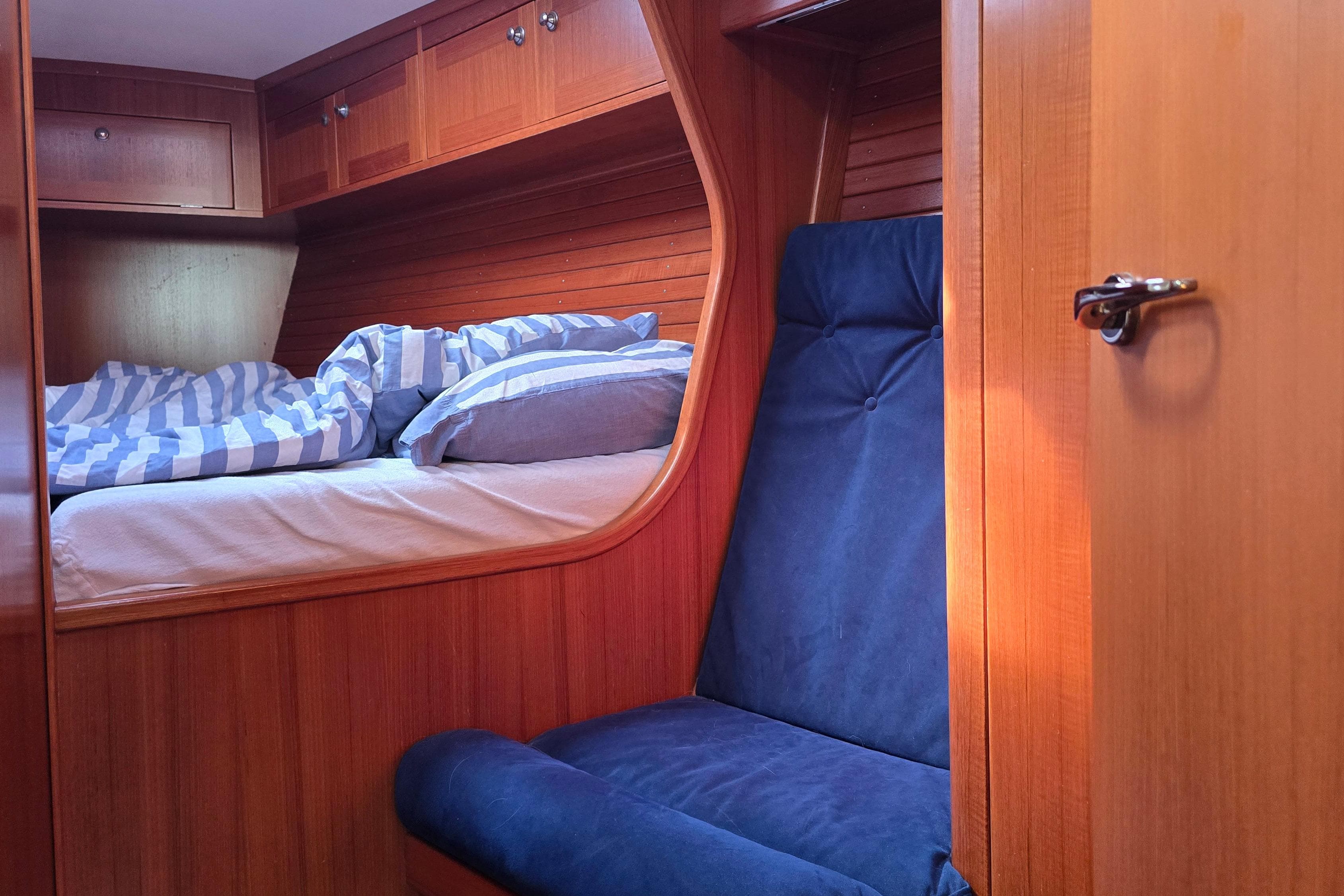 Cozy cabin interior of 2002 Comfortina 42 sailboat with wooden finish and blue seating.
