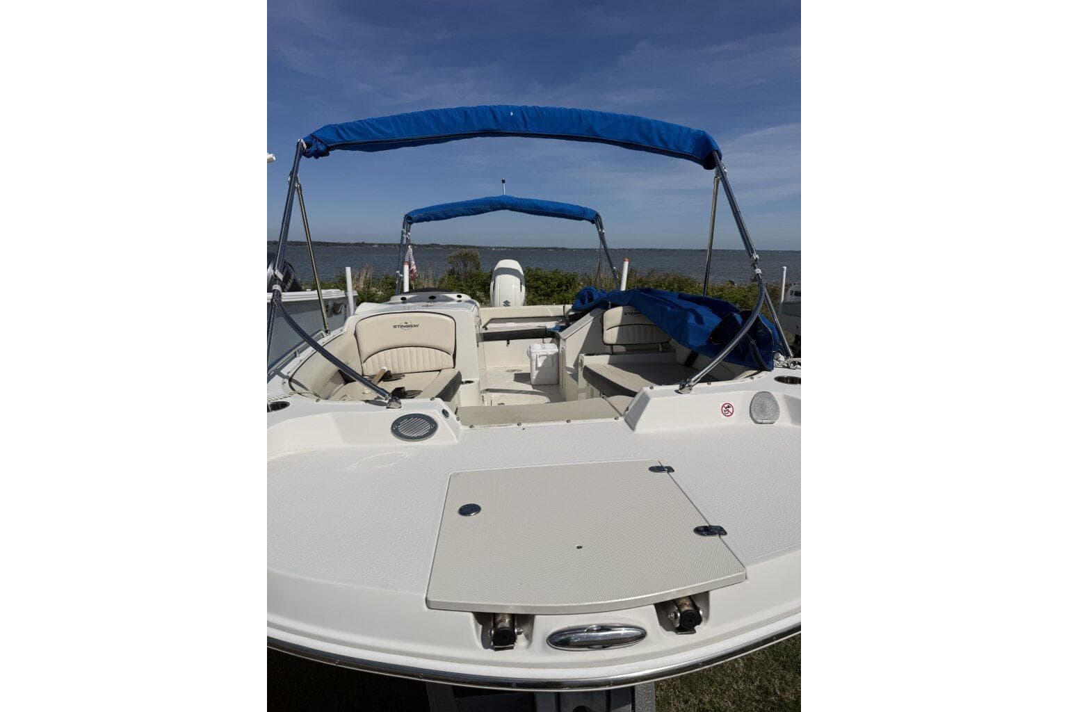 2021 Stingray 212 SC boat with blue canopy, docked by the water.