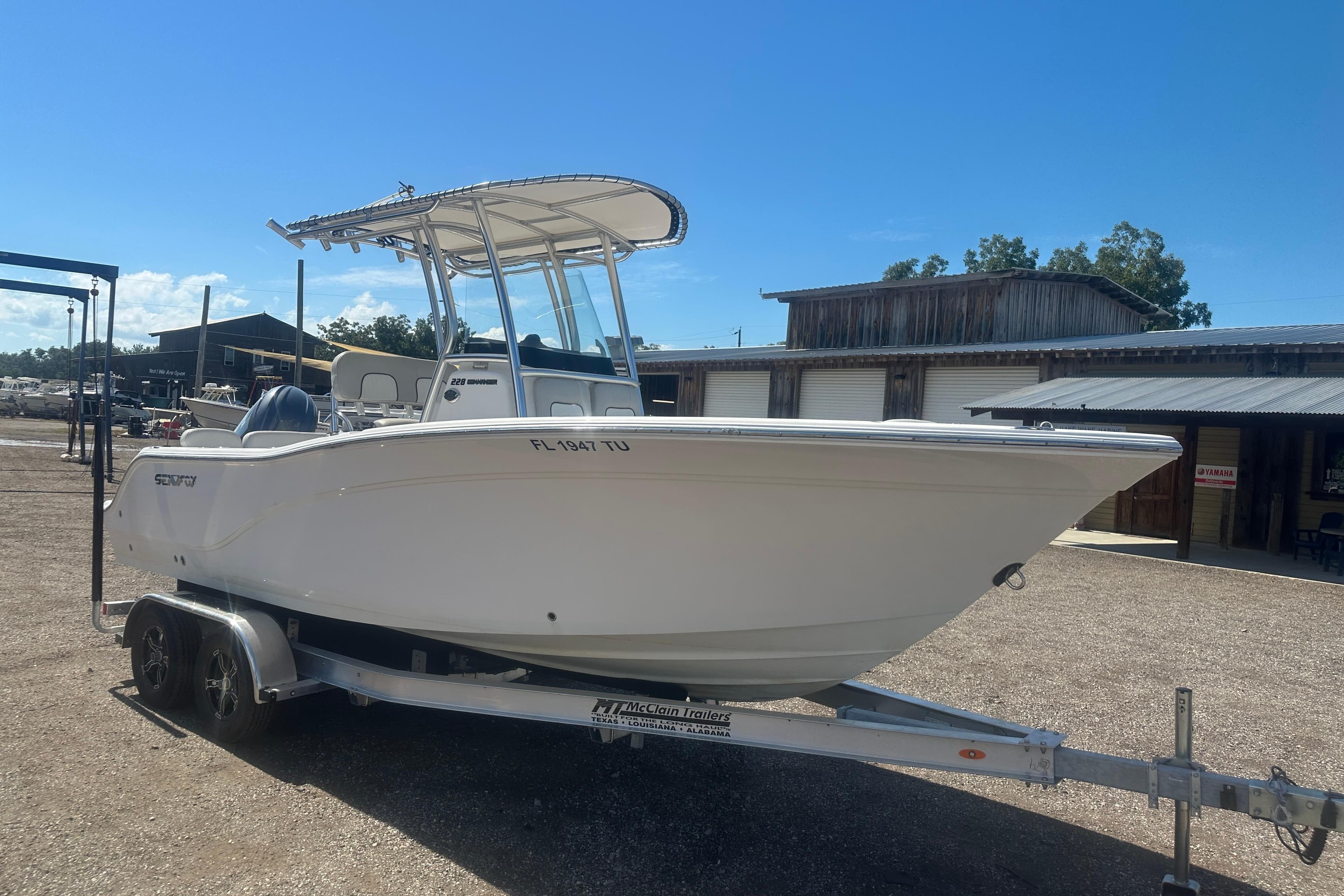 2023 Sea Fox 228 Commander boat on trailer, parked outdoors under clear blue sky.