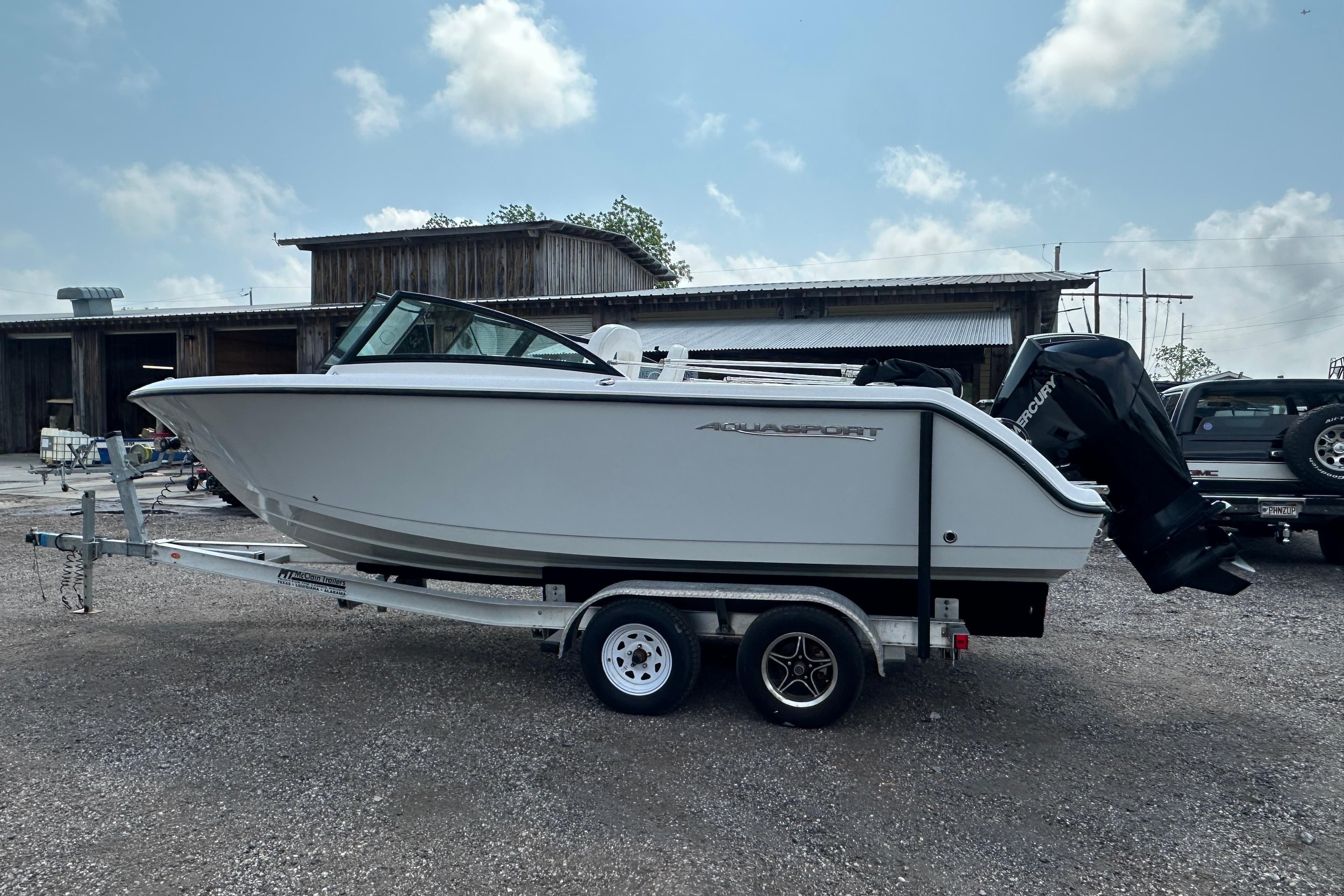 2024 Aquasport 2200 Dual Console boat on trailer, parked outdoors.