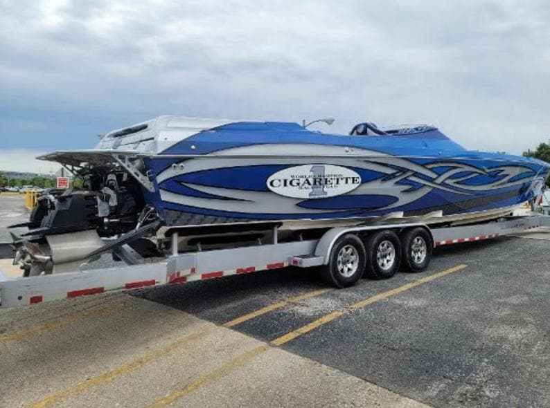 2009 Cigarette 46' Rider XP boat on trailer, blue and white design, parked outdoors.