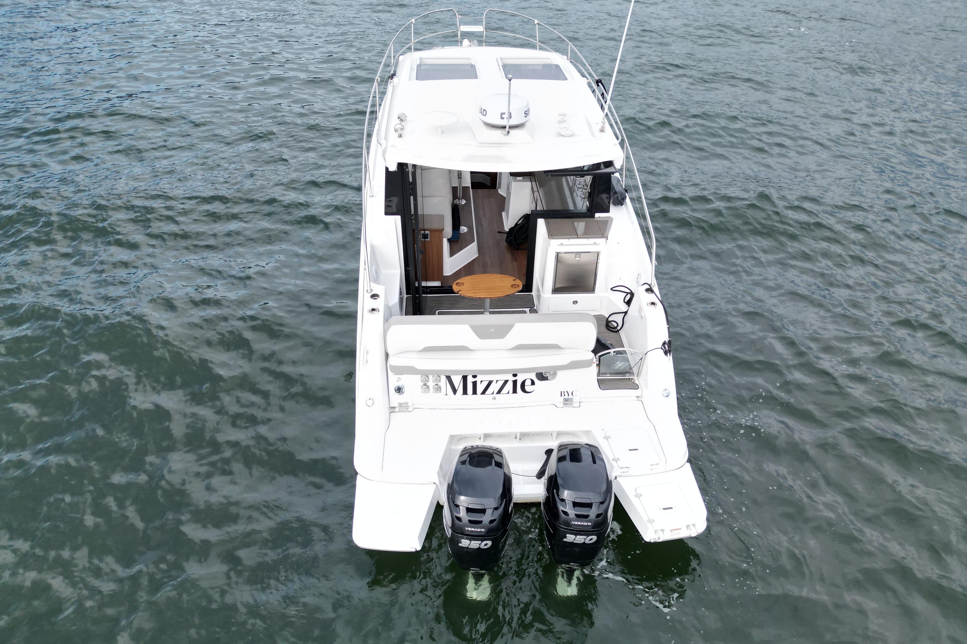 2022 Four Winns V355 Coupe OB boat on water, rear view with twin engines.