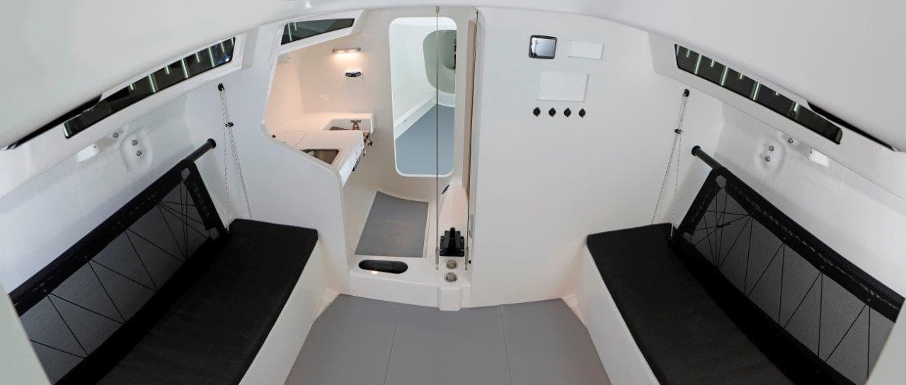 Modern interior of 2024 M.A.T. 1220 sailboat with black seating and white walls.